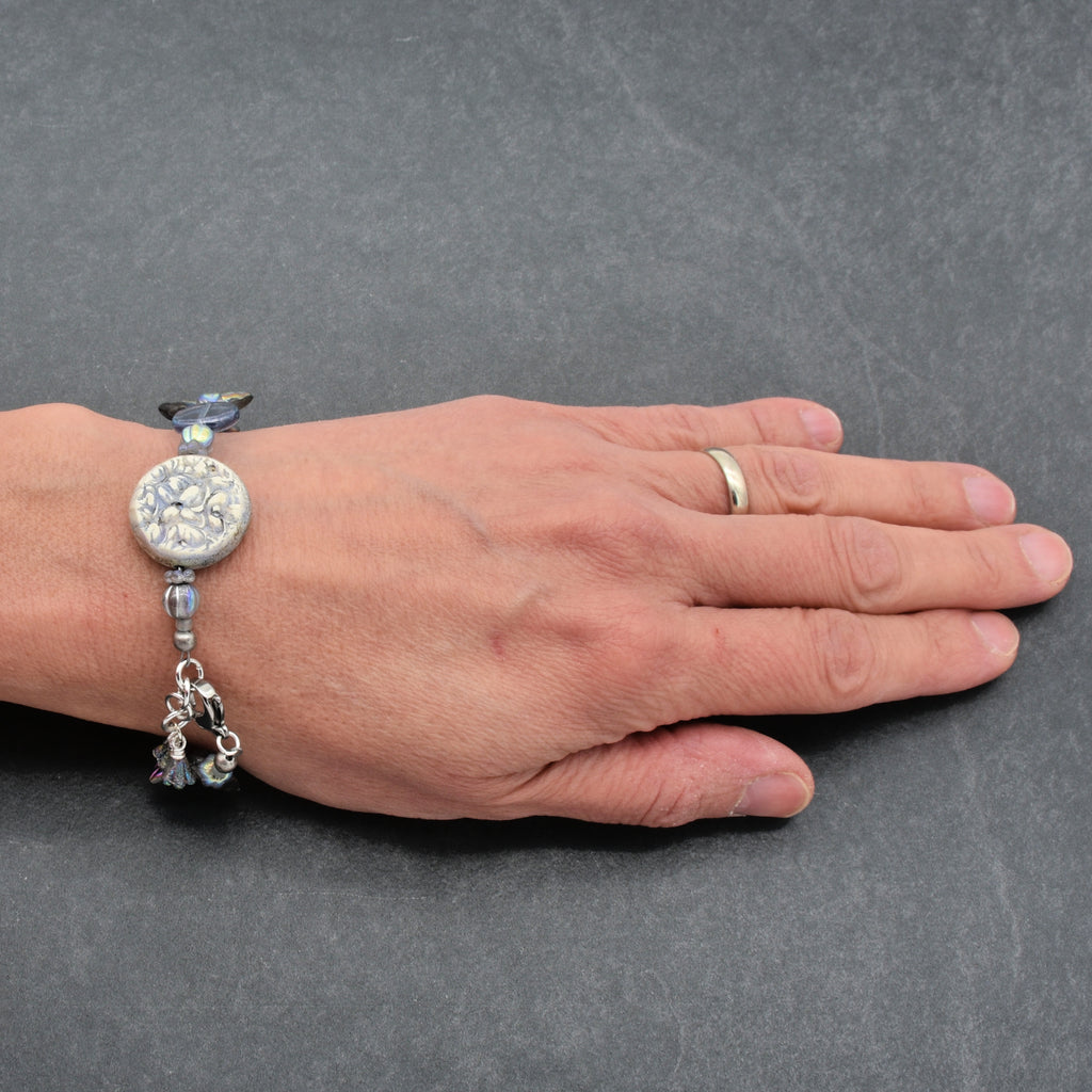 Hand wearing a bracelet with charms on a gray background