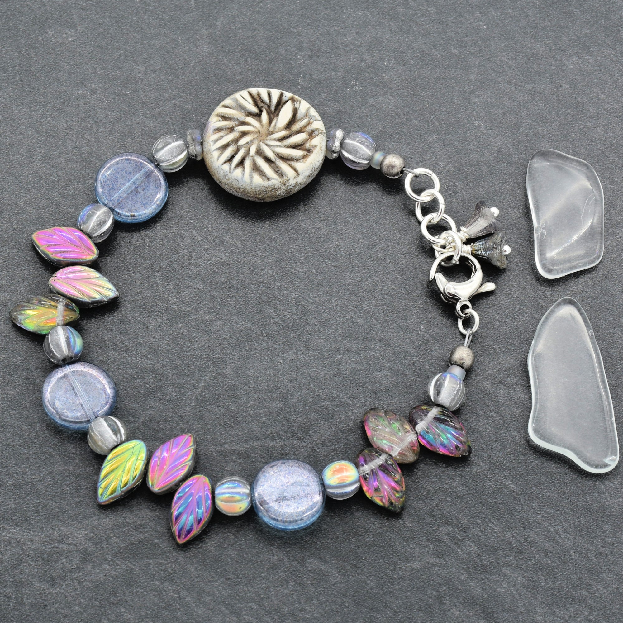 Bracelet with colorful beads and a floral charm on a dark surface