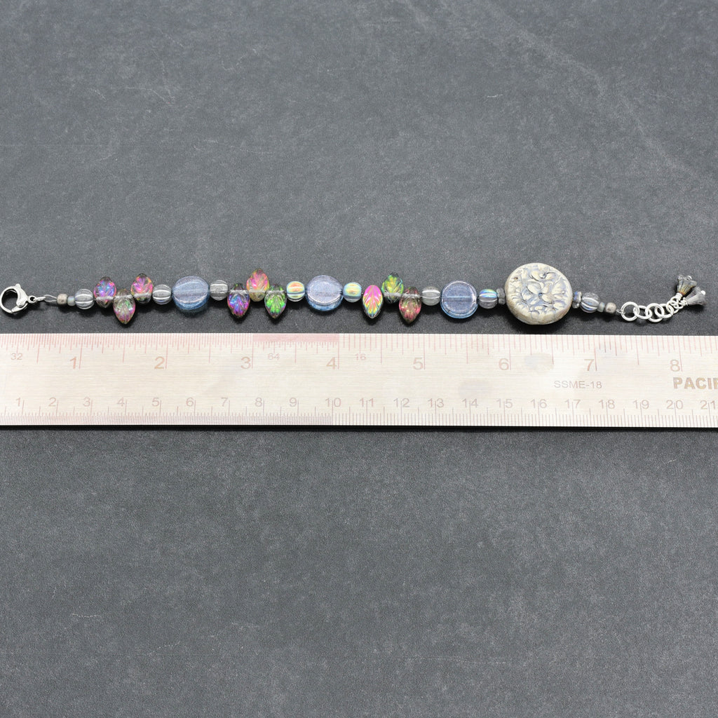 Beaded bracelet on a ruler for size reference against a gray background