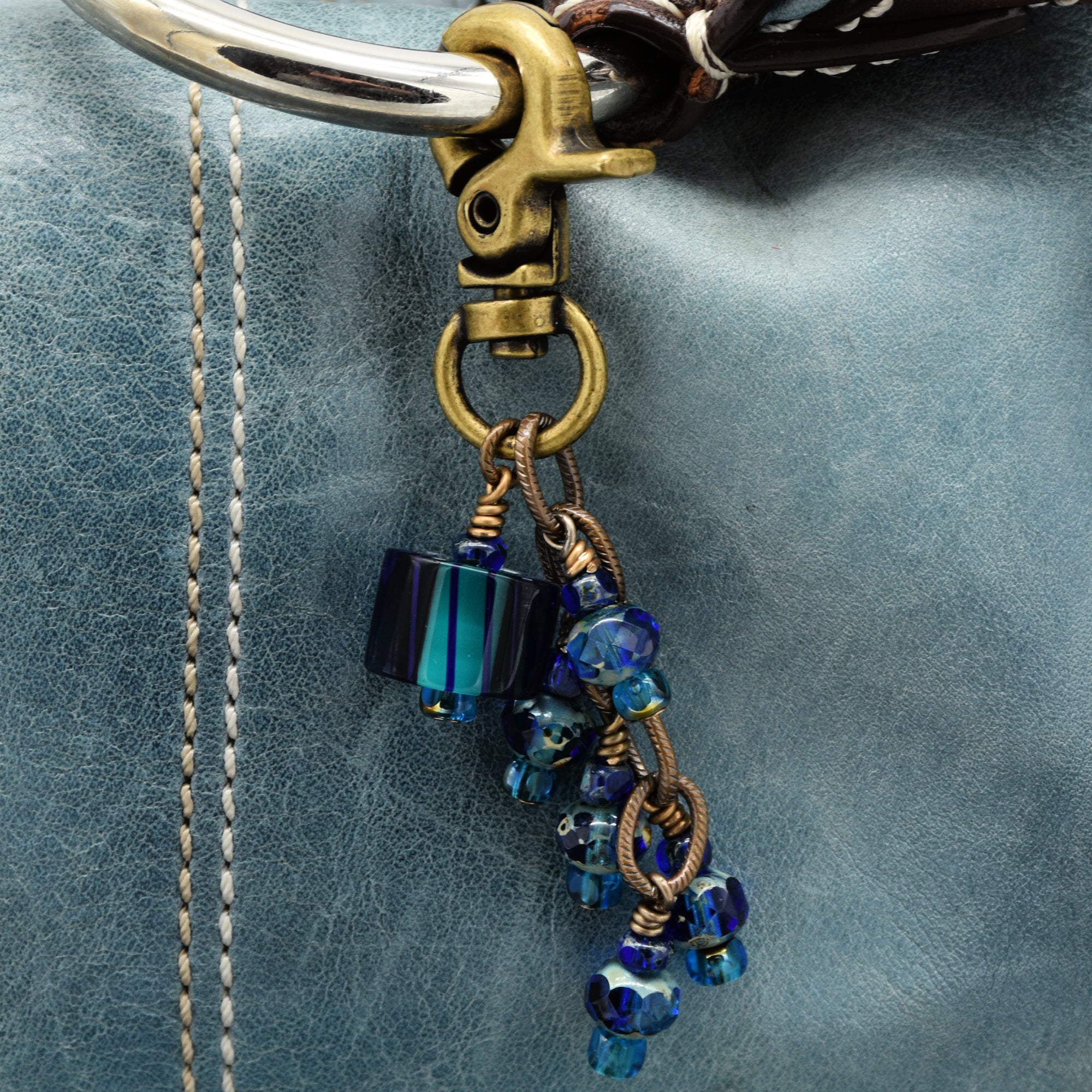 Close-up of a decorative keychain with blue beads on a textured surface