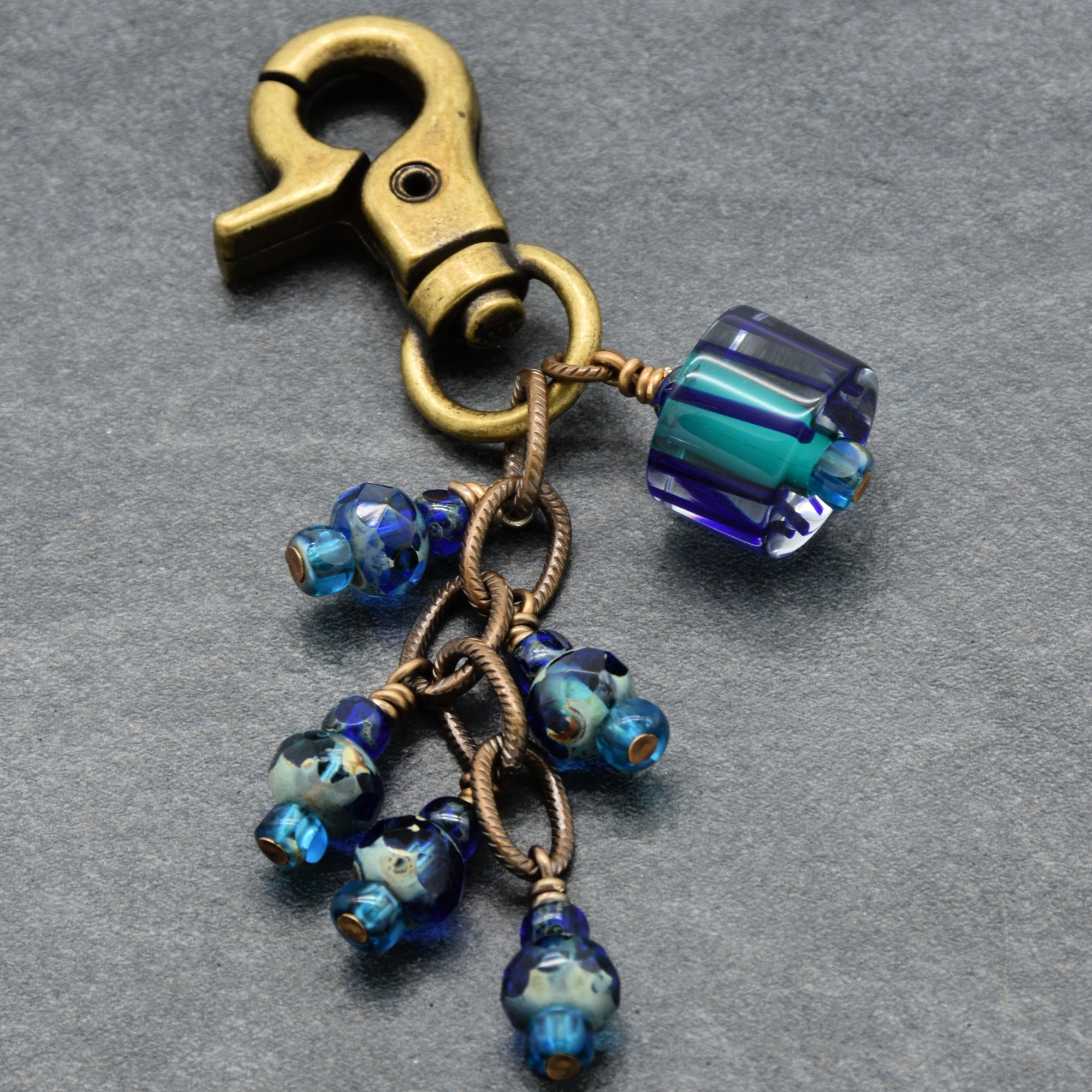 Keychain with blue beads and brass clasp on a gray background