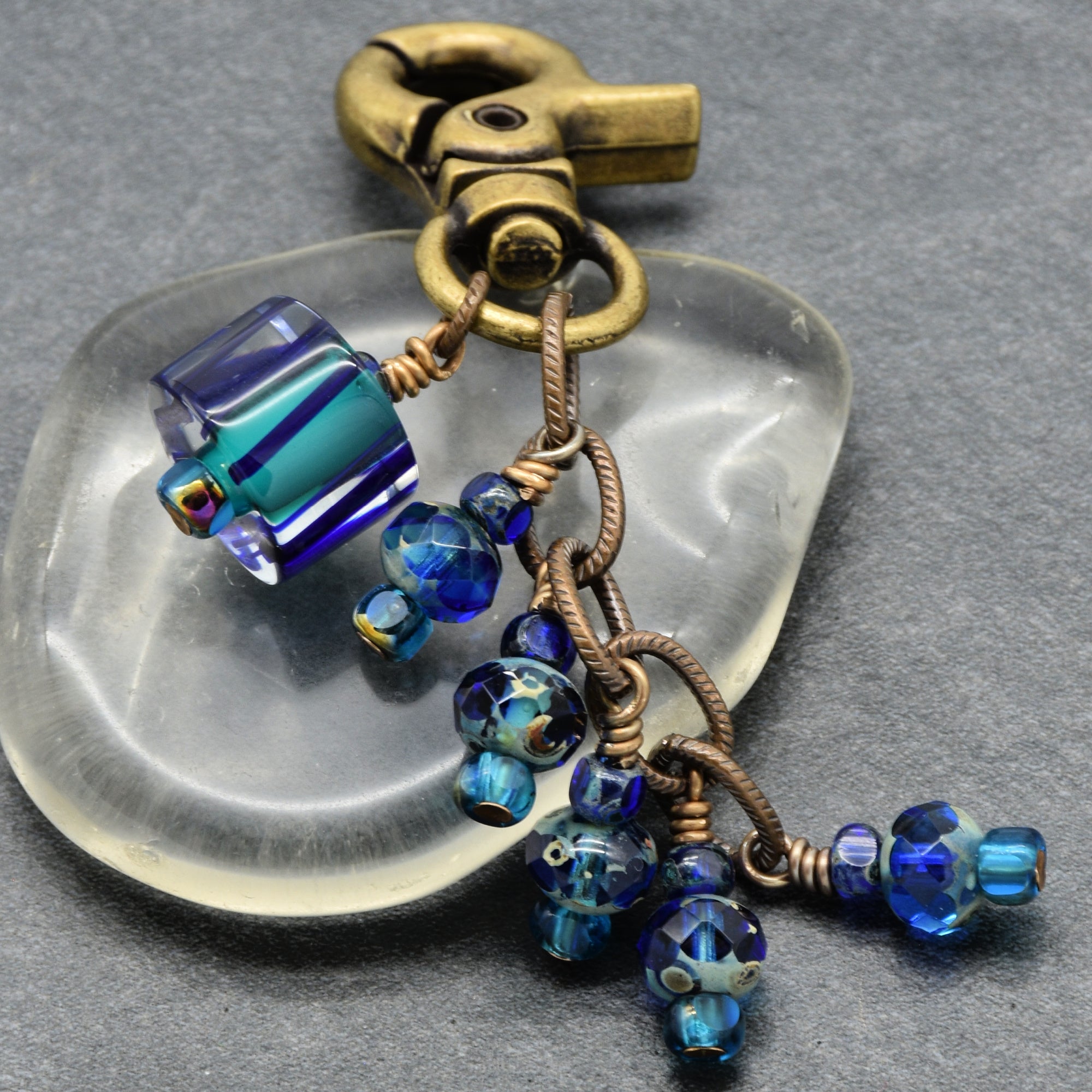Keychain with blue beads and a metallic clasp on a gray background