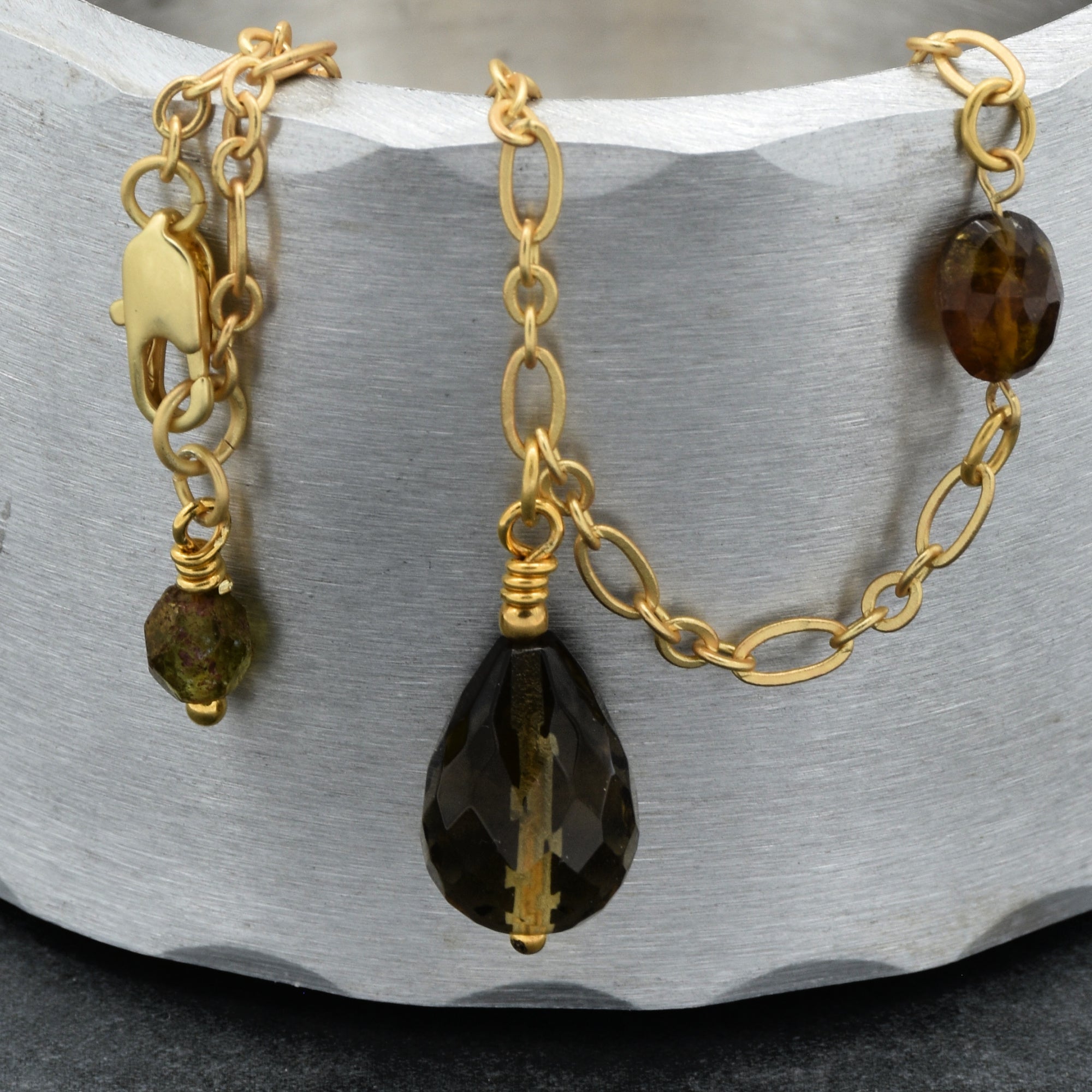 This image shows a bracelet. The jewelry has a chain with a clasp on one end, which is typical for bracelets, along with decorative beads and a larger pendant-like charm.