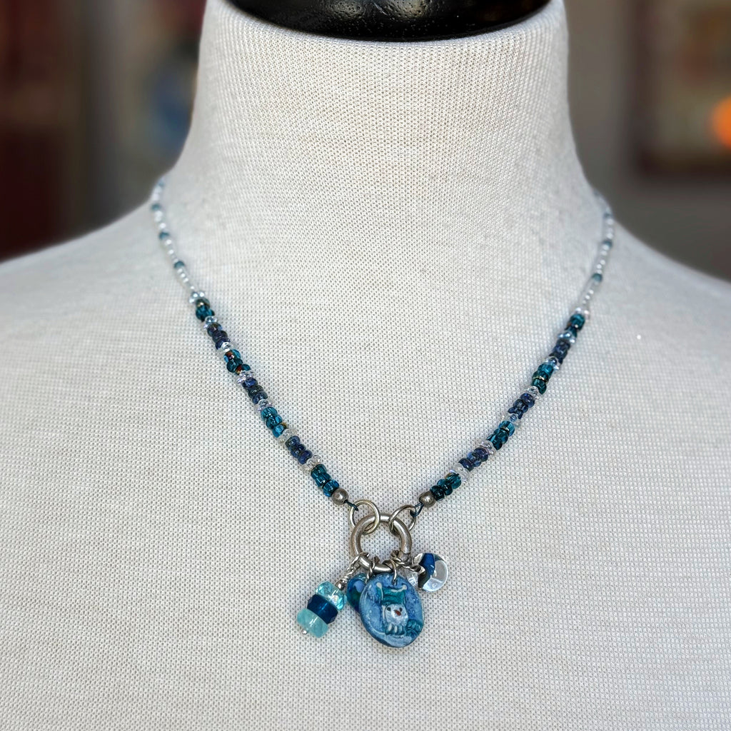 Blue beaded necklace with charms on a mannequin bust.