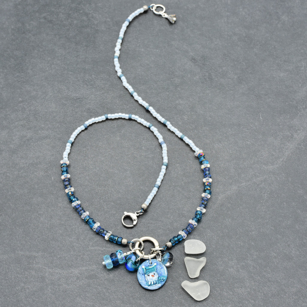 Festive necklace with blue beads and charms on a gray background