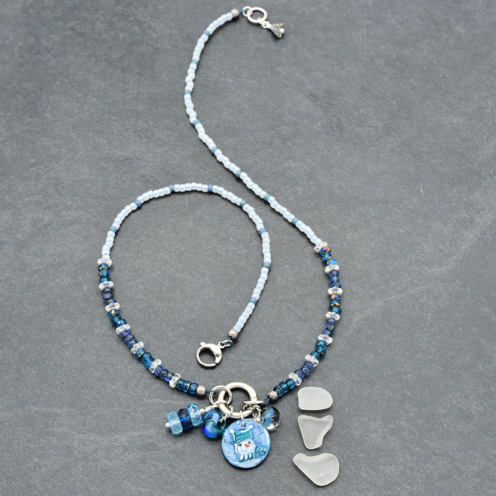 Festive necklace with blue beads and charms on a gray background