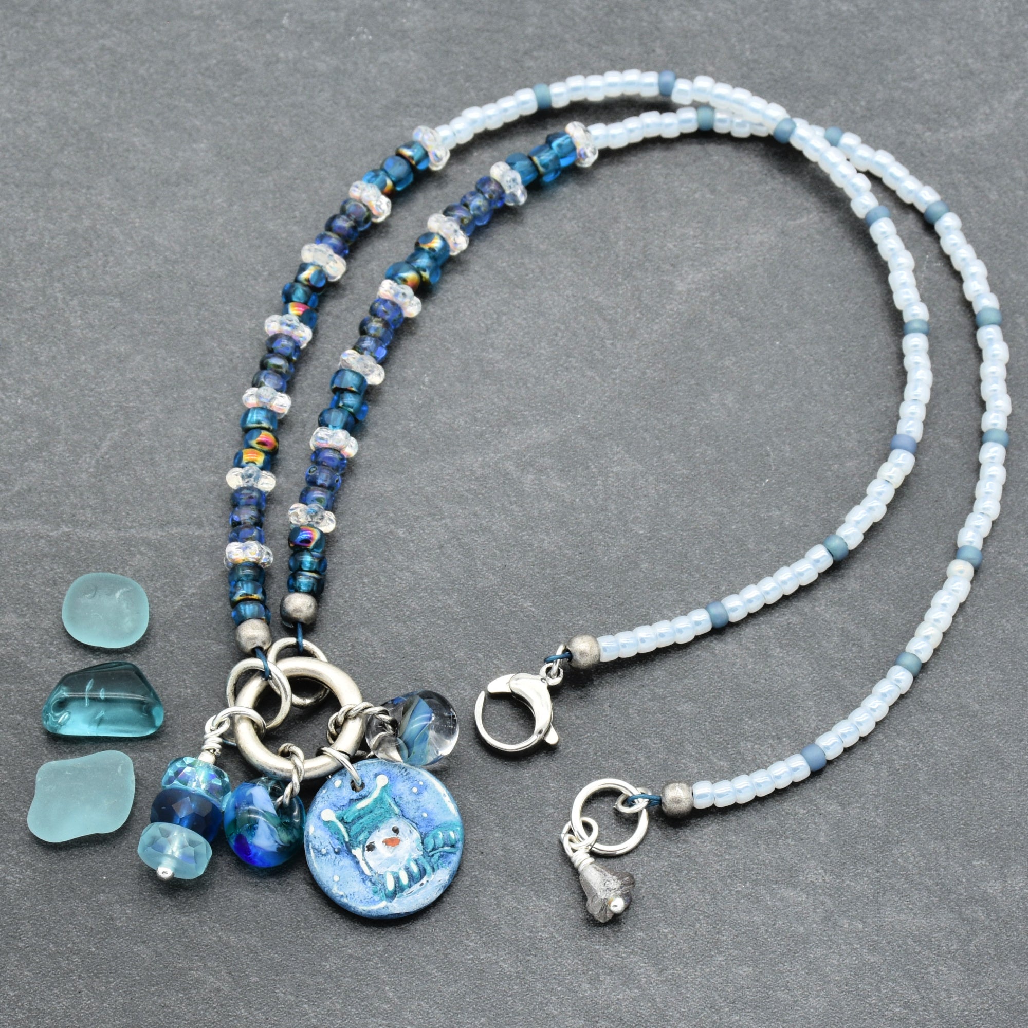 Festive necklace with blue beads and charms on a gray surface