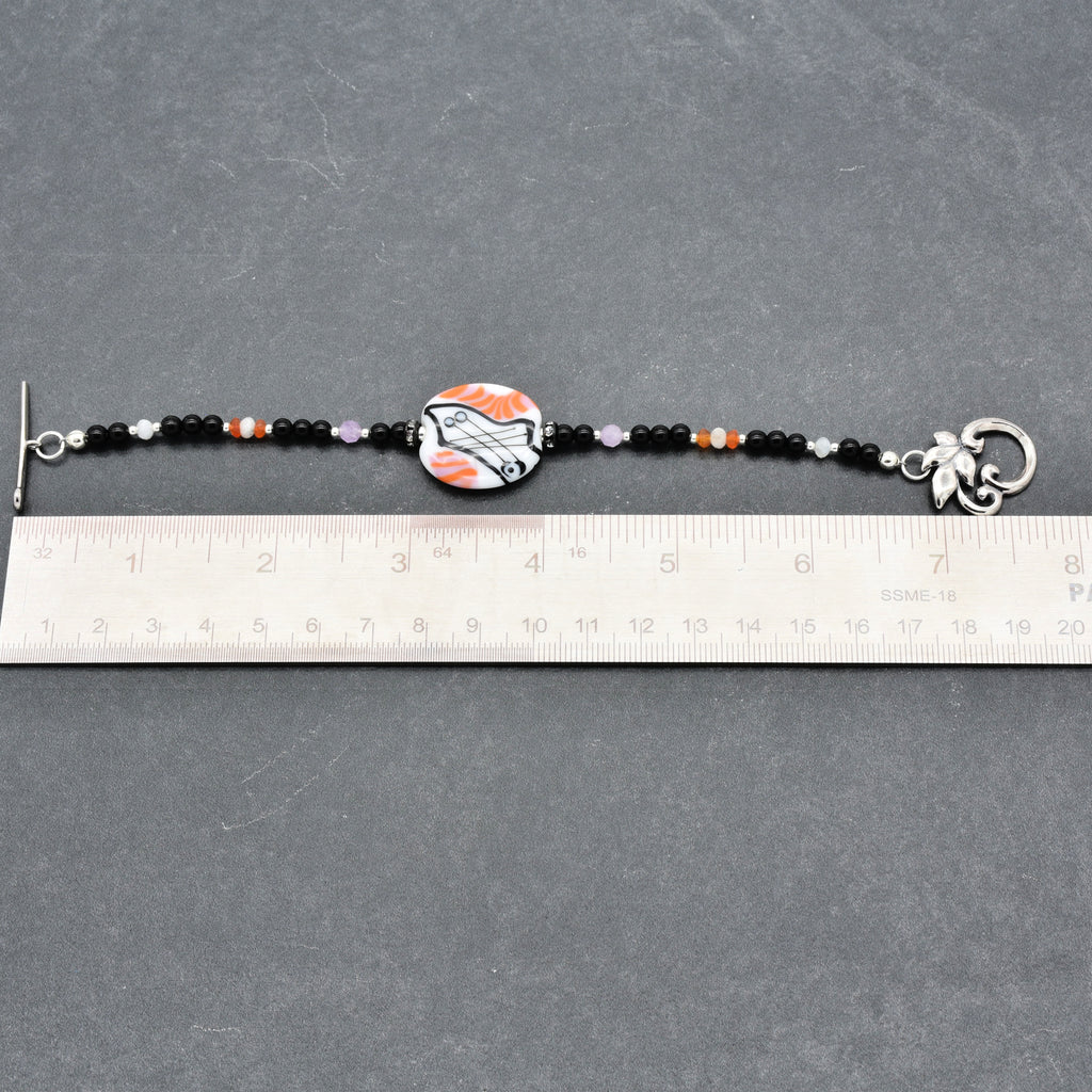 Beaded bracelet with a decorative clasp on a gray surface, measured against a ruler.