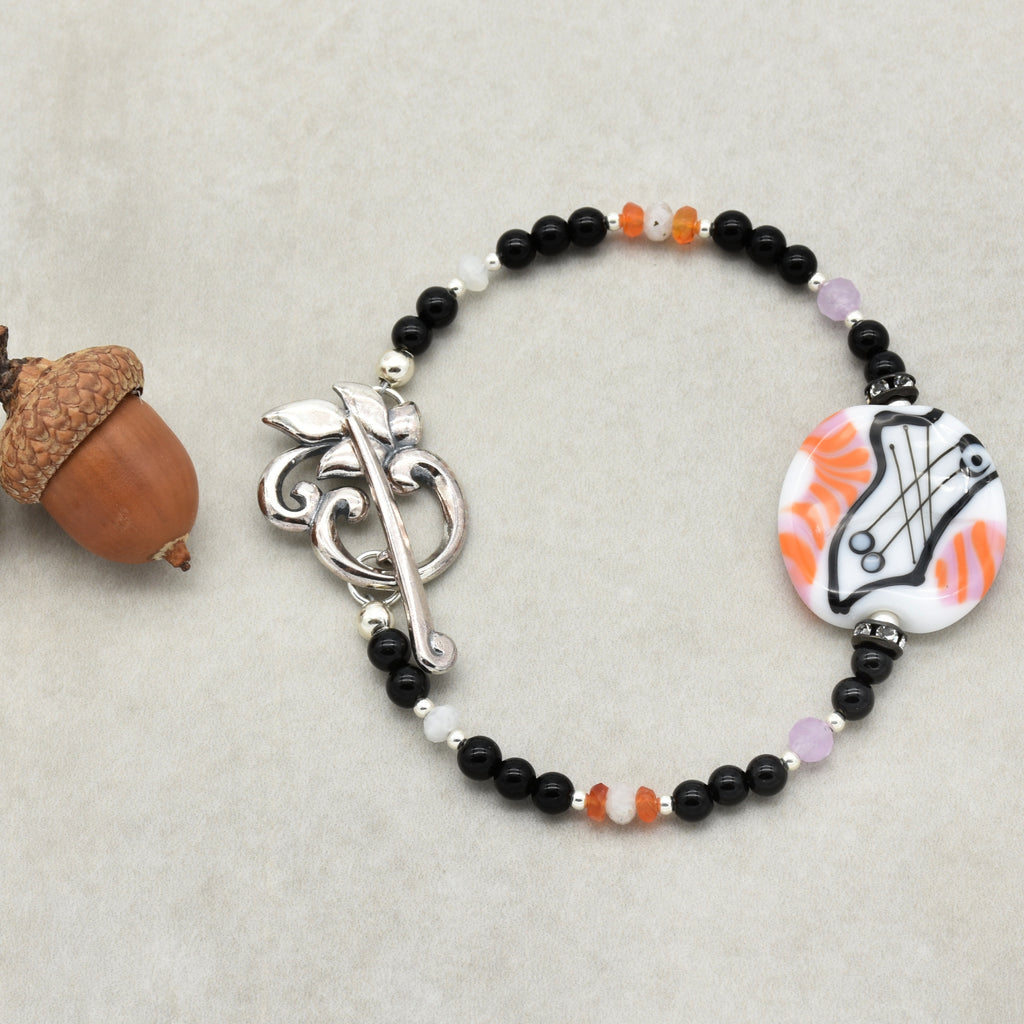 Bracelet with black beads, a silver clasp, and a decorative element on a light gray background