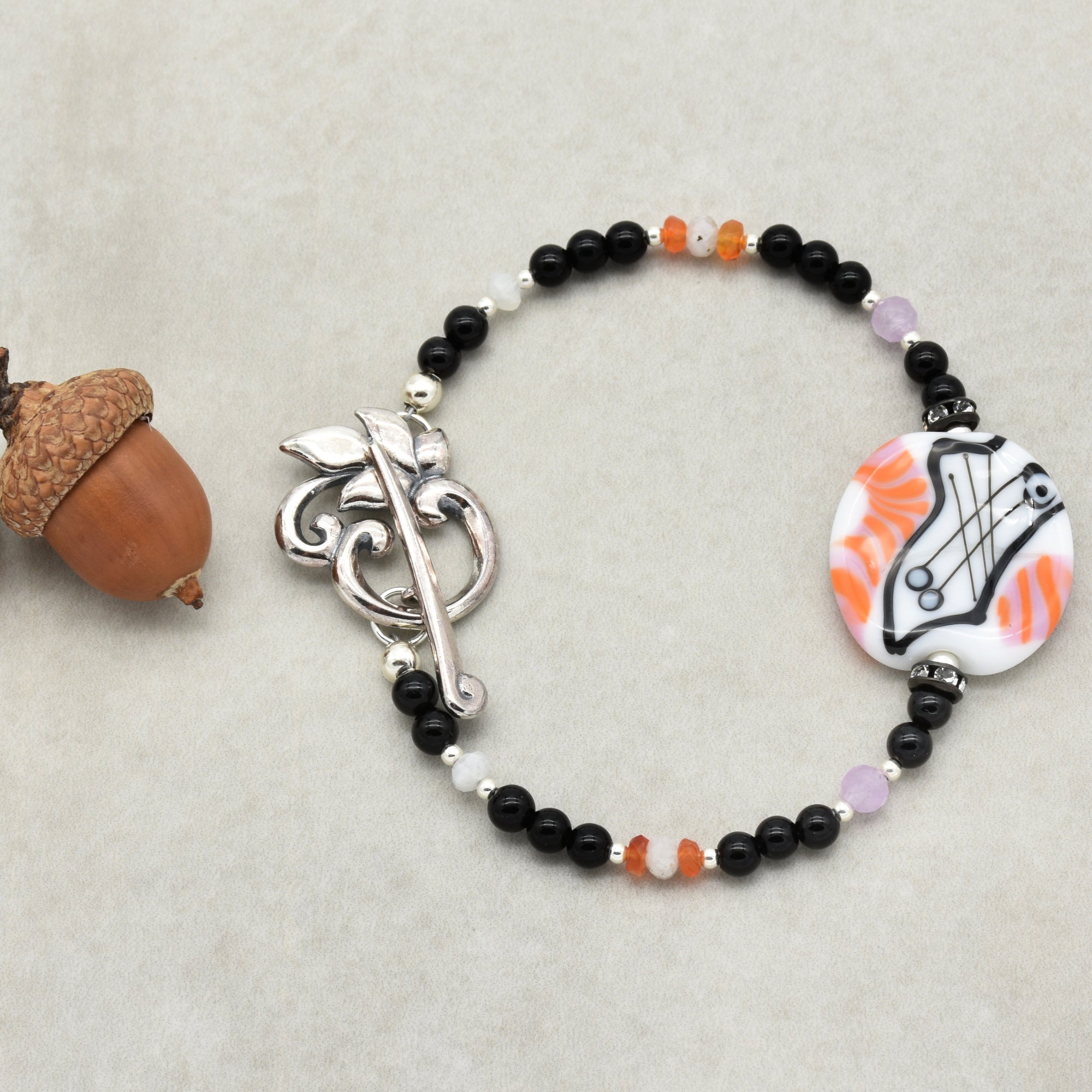 Bracelet with black beads, a silver clasp, and a decorative element on a light gray background