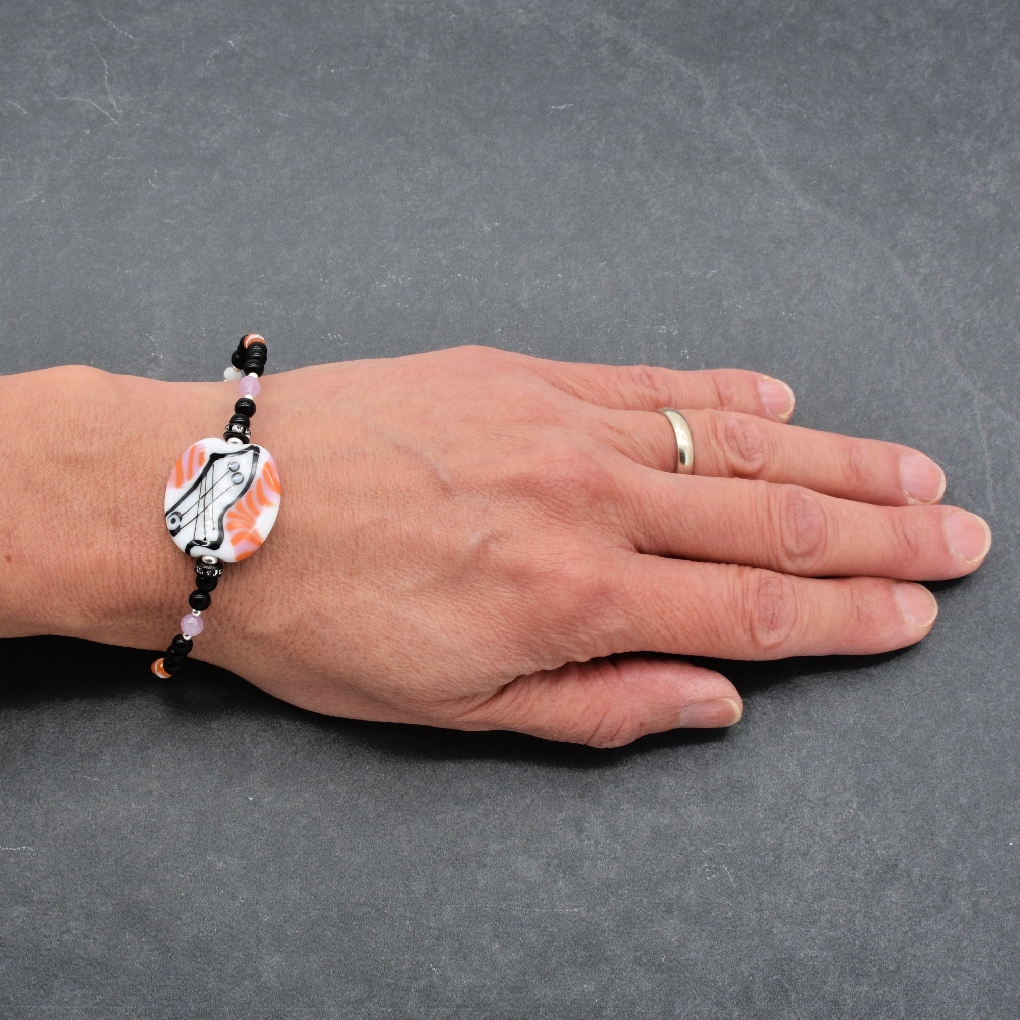 Hand wearing a bracelet on a gray background
