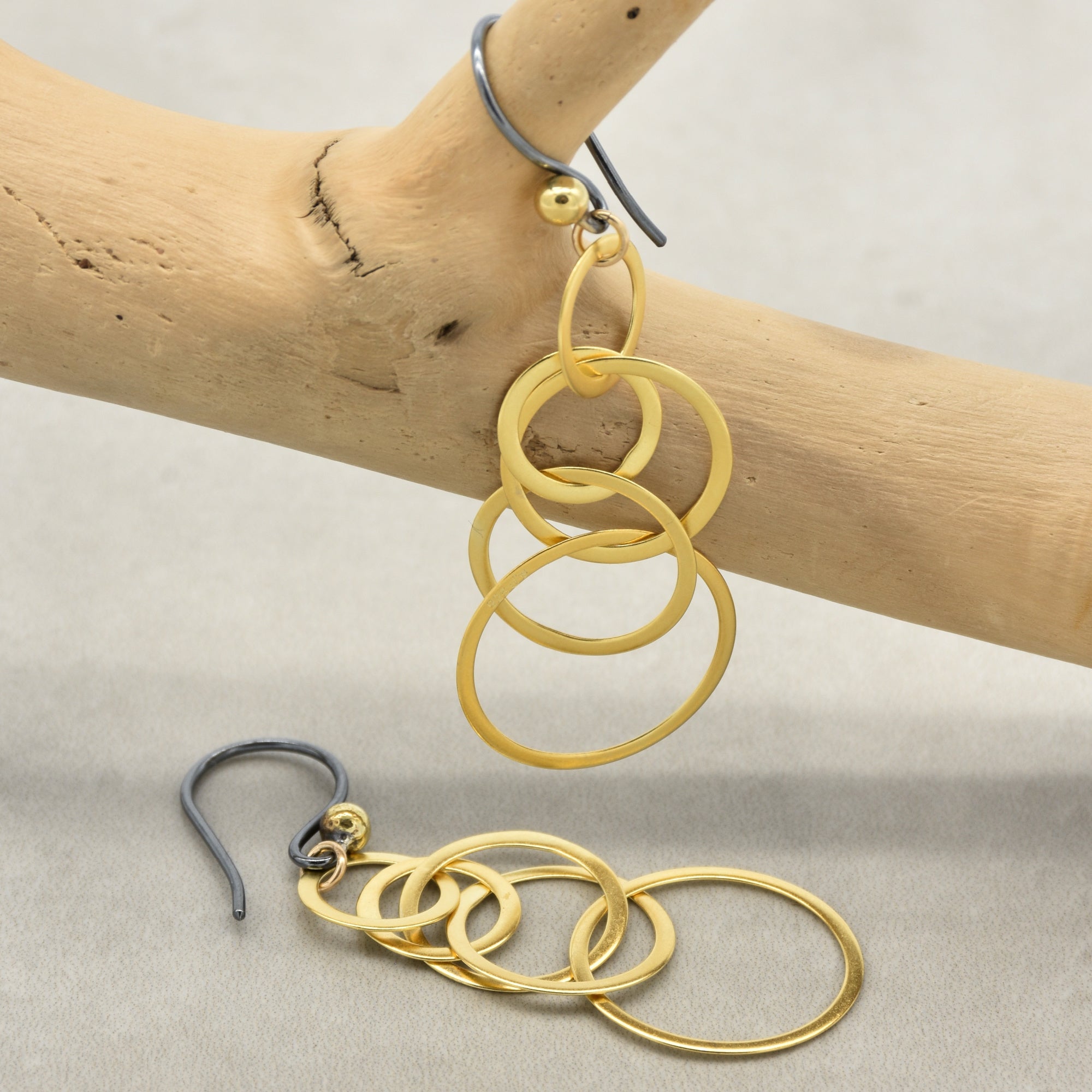 Gold interlocking hoop earrings with black silver ear wires on a branch- made with love by Ruby Acorn.