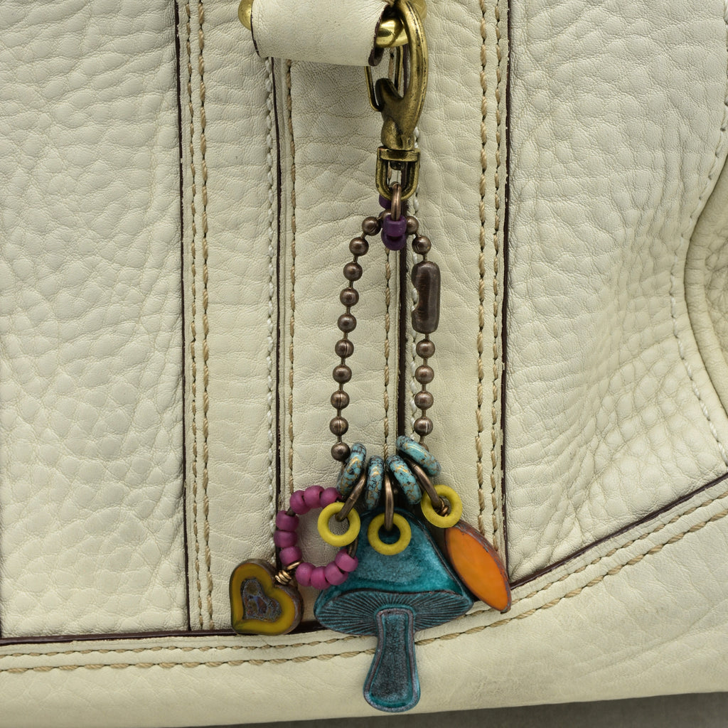 Colorful keychain with charms attached to a beige leather bag.