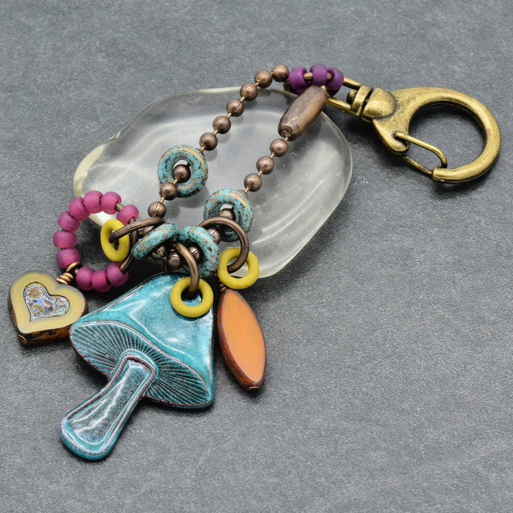 Colorful keychain with mushroom charm on a gray background