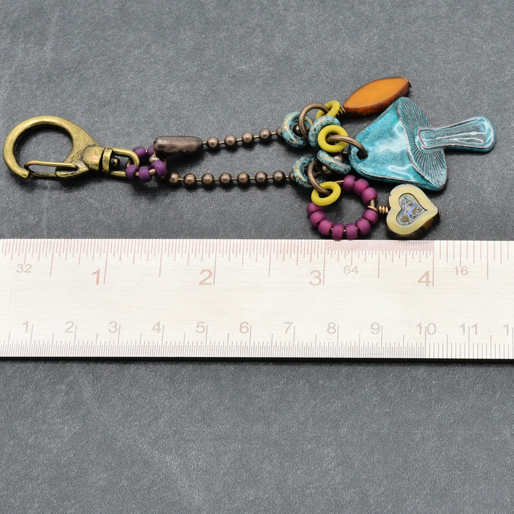 Colorful keychain with charms on a gray surface with a ruler for scale.