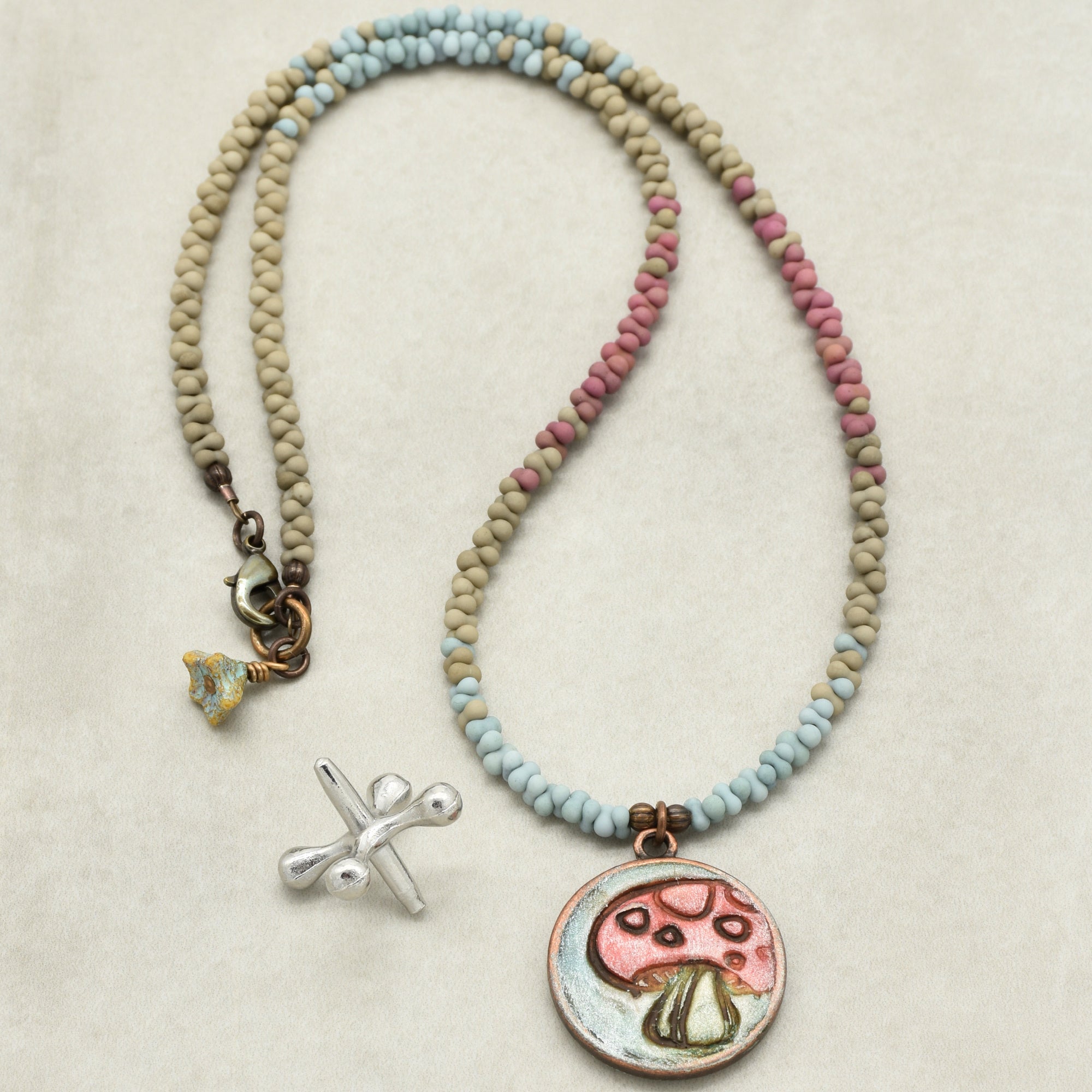 Necklace with colorful beads and a mushroom pendant on a beige background