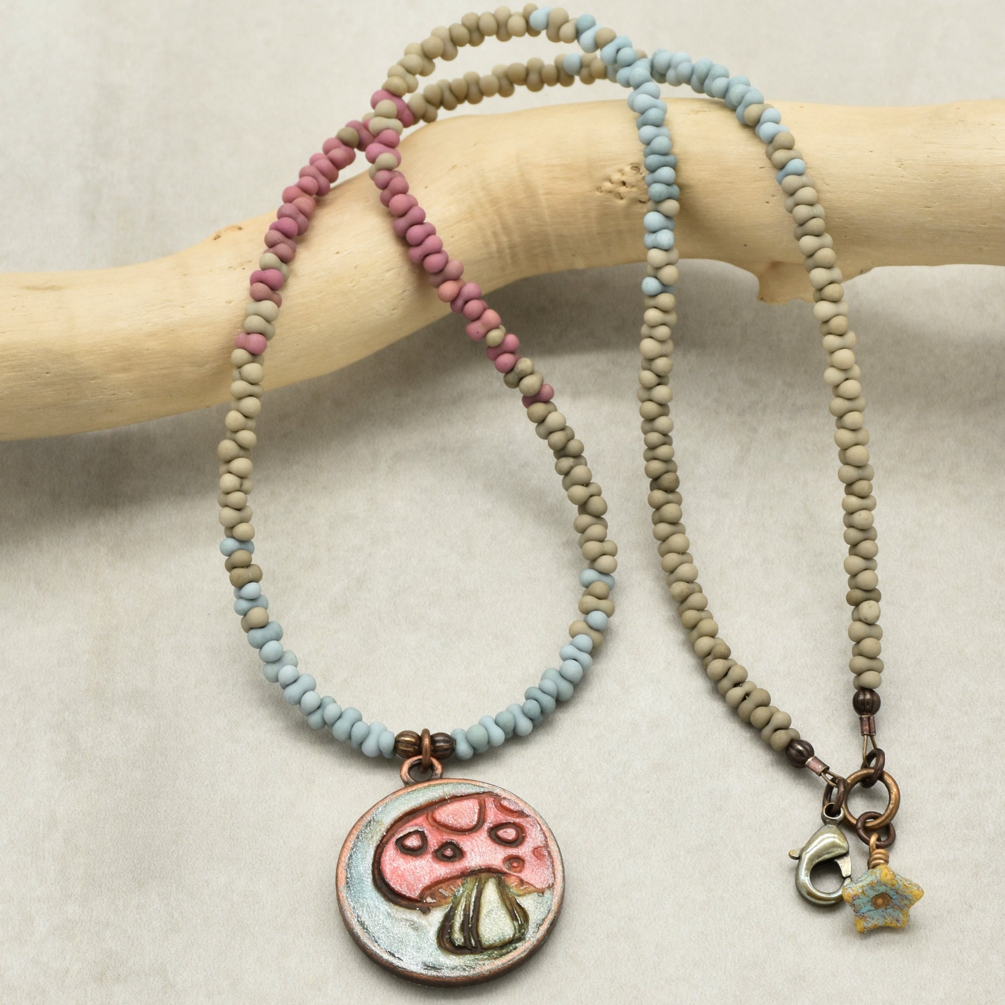 Beaded necklace with charms on a wooden stick against a neutral background