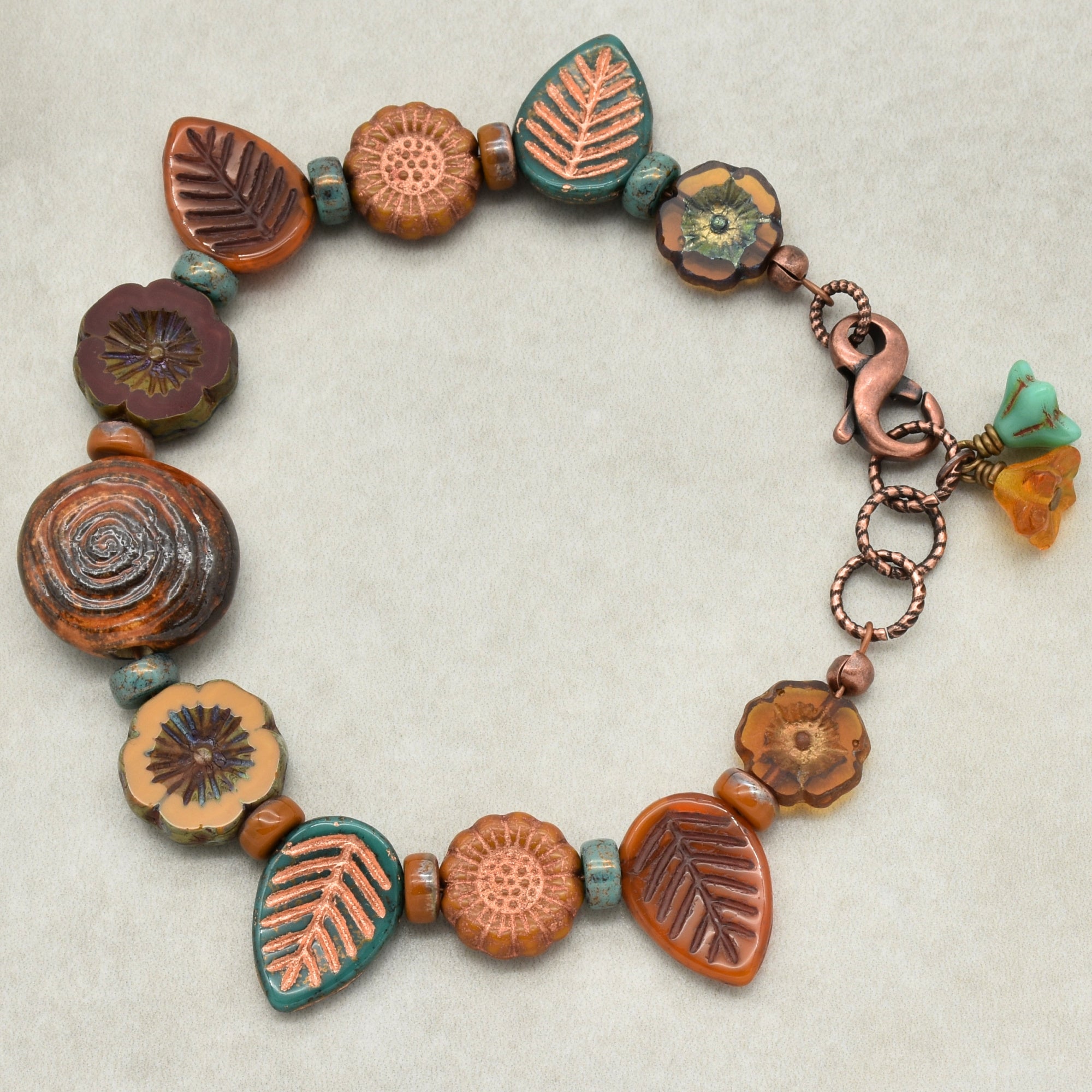 Ceramic bead bracelet with floral and leaf designs on a neutral background