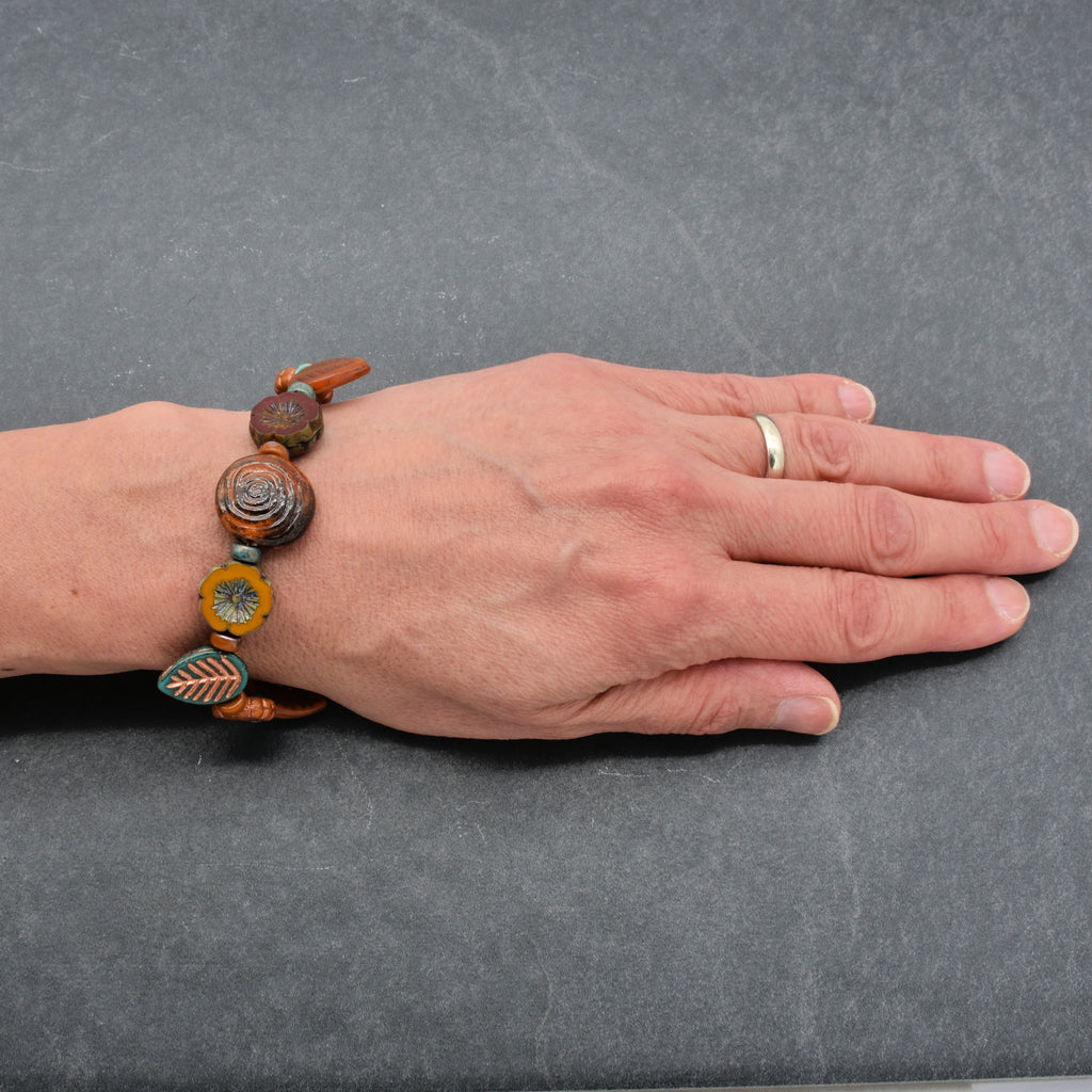 Hand wearing a beaded bracelet on a gray background
