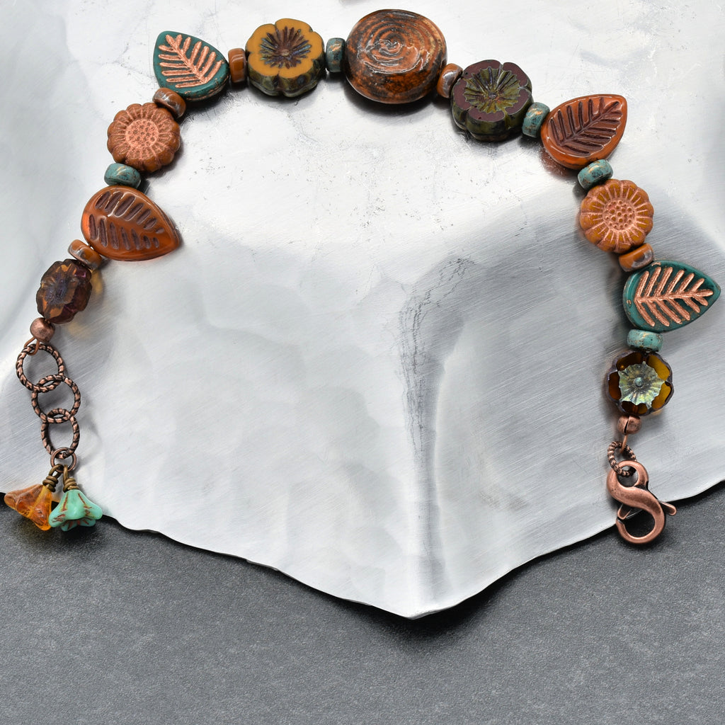 Beaded bracelet with leaf and floral patterns on a white fabric background