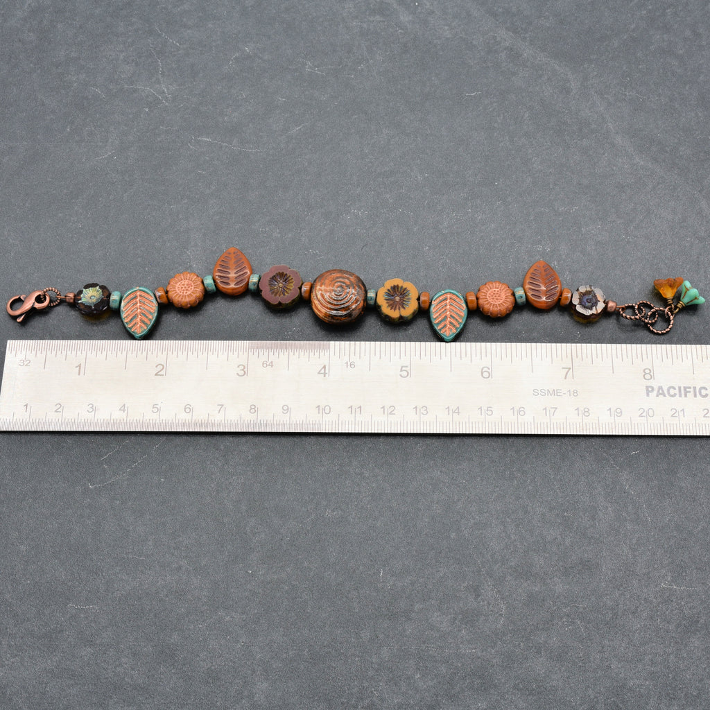 Bracelet with decorative beads on a gray surface with a ruler for scale.