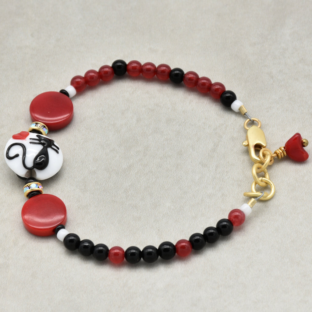 Beaded bracelet with red, black, and white beads on a beige background