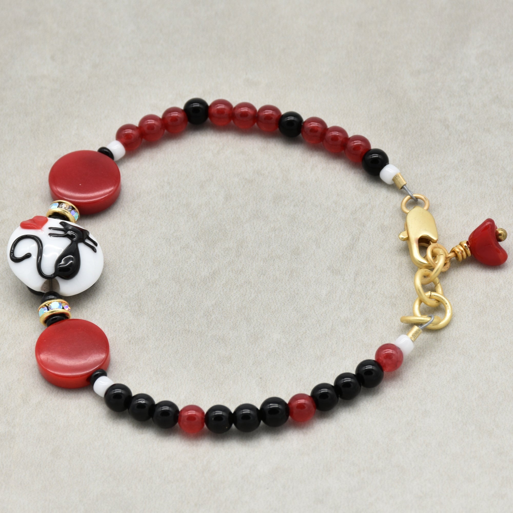 Beaded bracelet with red, black, and white beads on a beige background