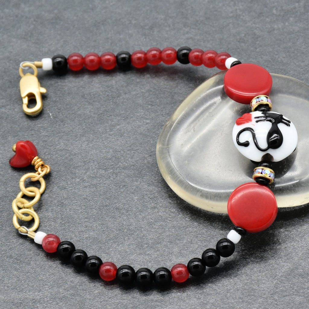 Bracelet with red, black, and gold beads on a gray background