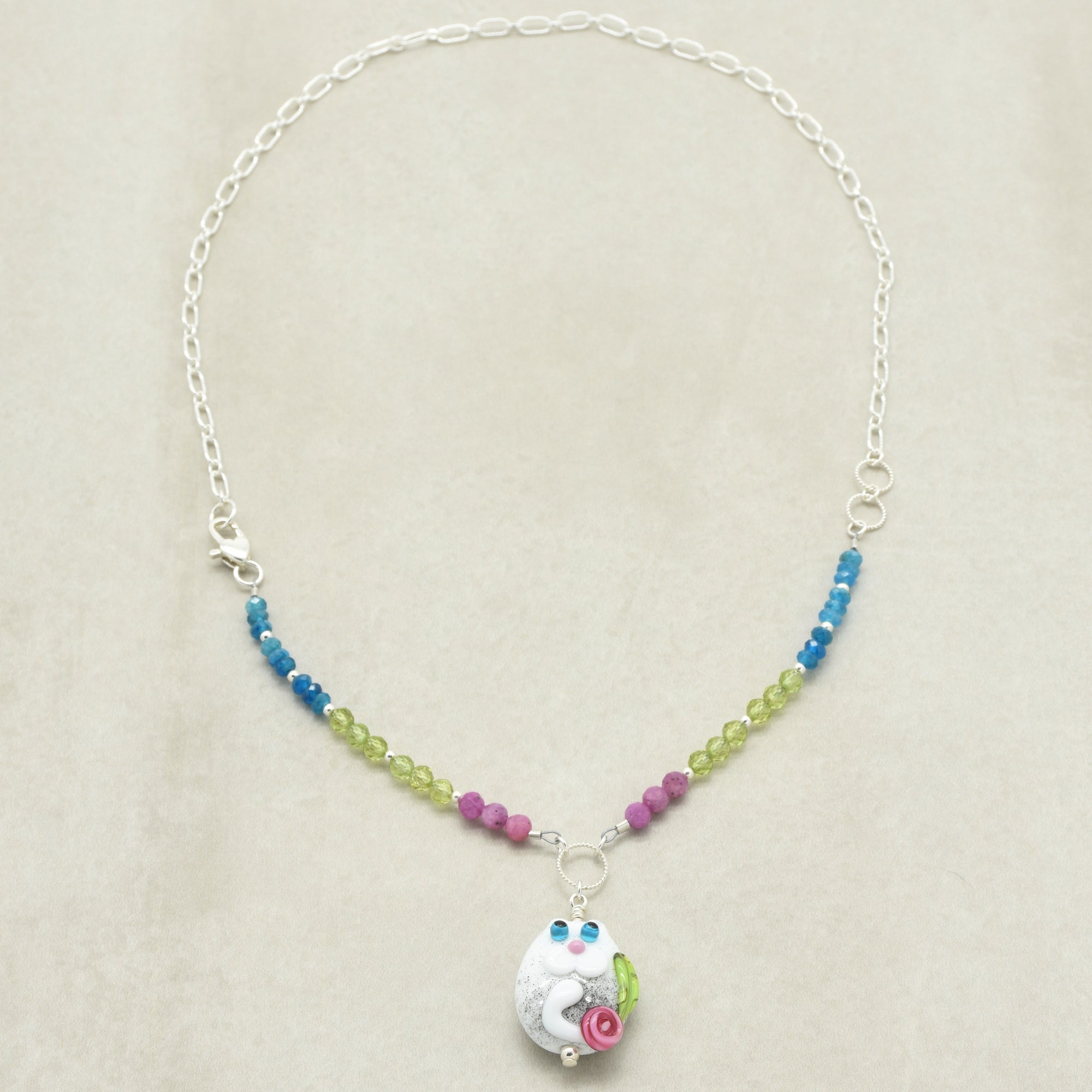 Necklace with colorful beads and a small pendant on a beige background
