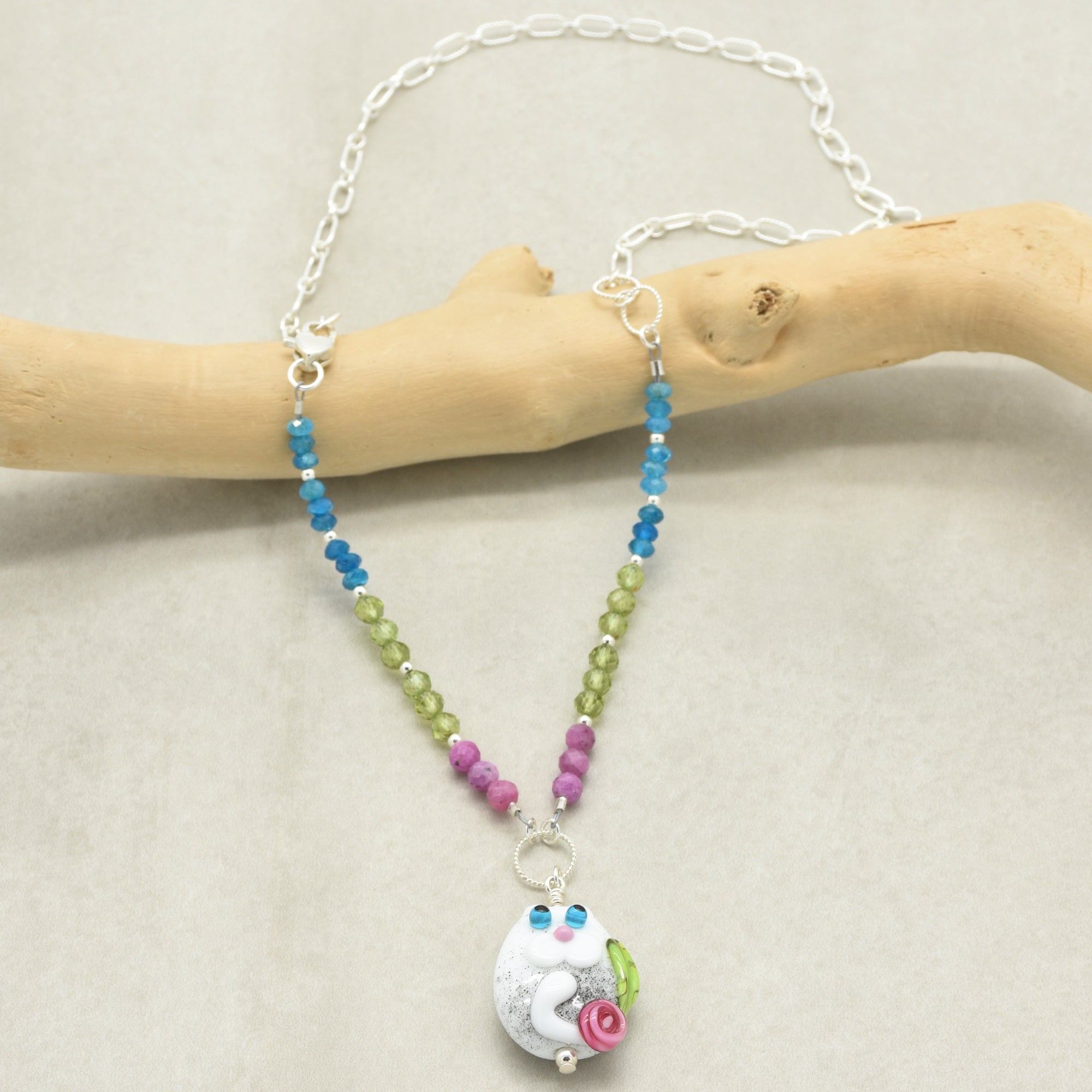 Beaded necklace with a colorful pendant on a wooden branch