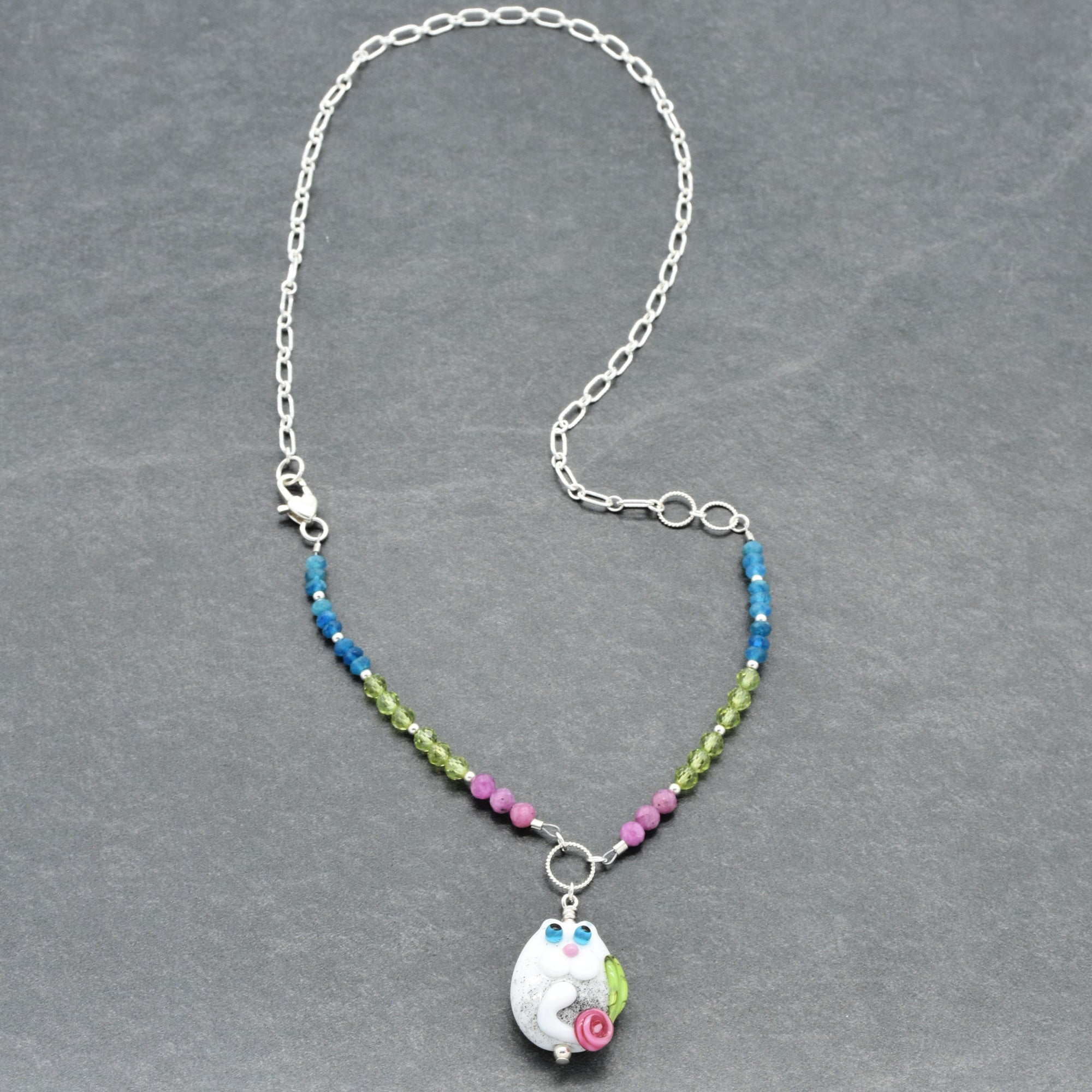 Necklace with colorful beads and a cat-shaped pendant on a gray background