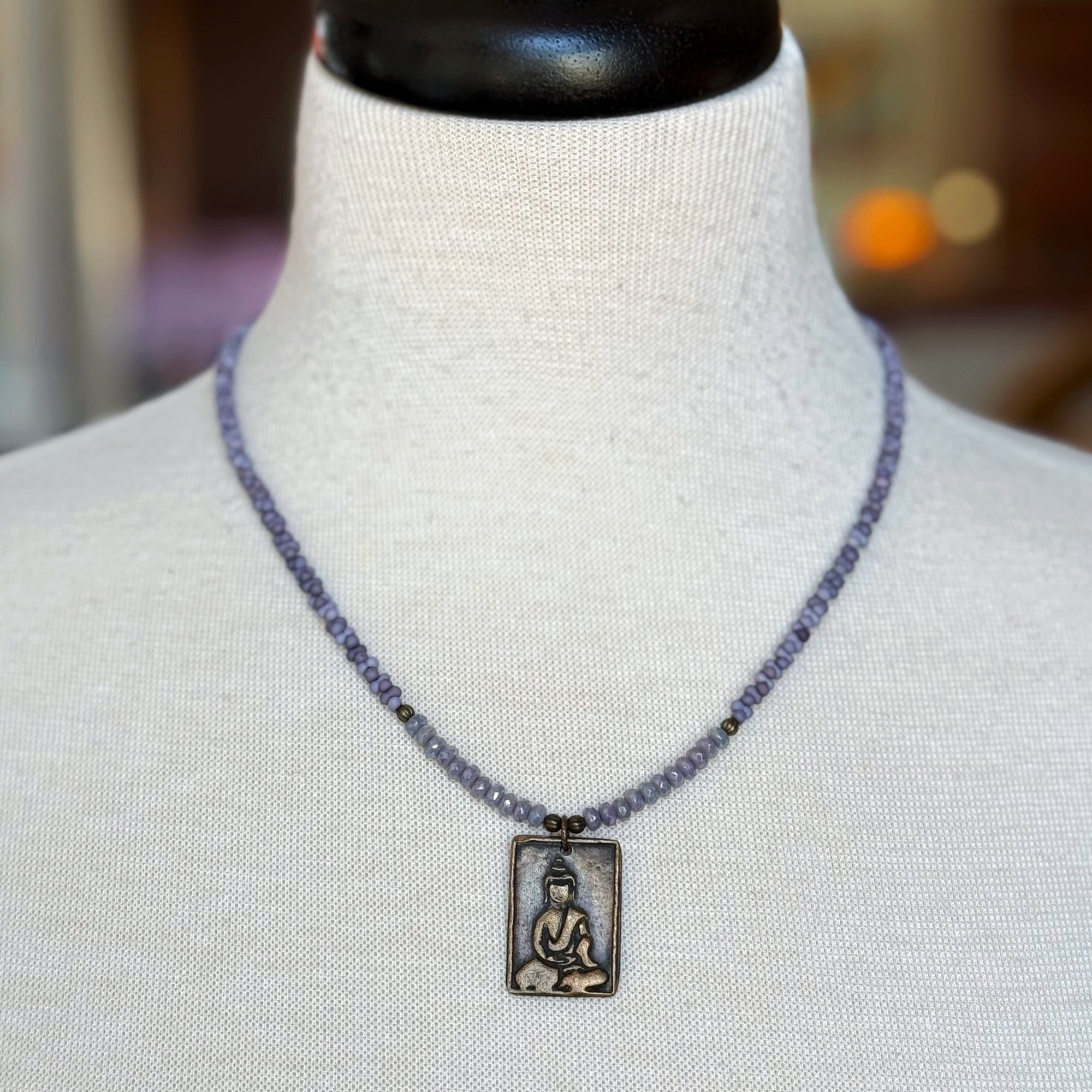 Necklace with a Buddha pendant on a mannequin bust