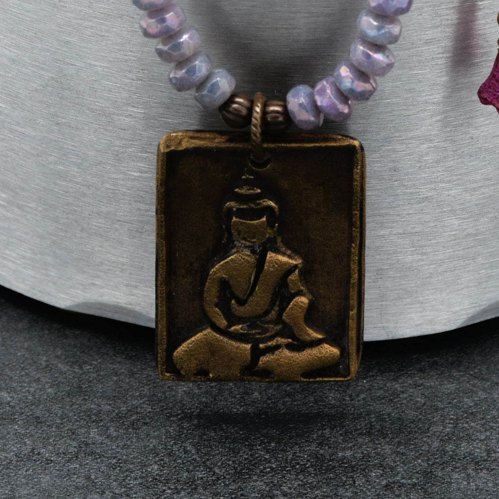 Necklace with a bronze pendant featuring a Buddha on a textured surface