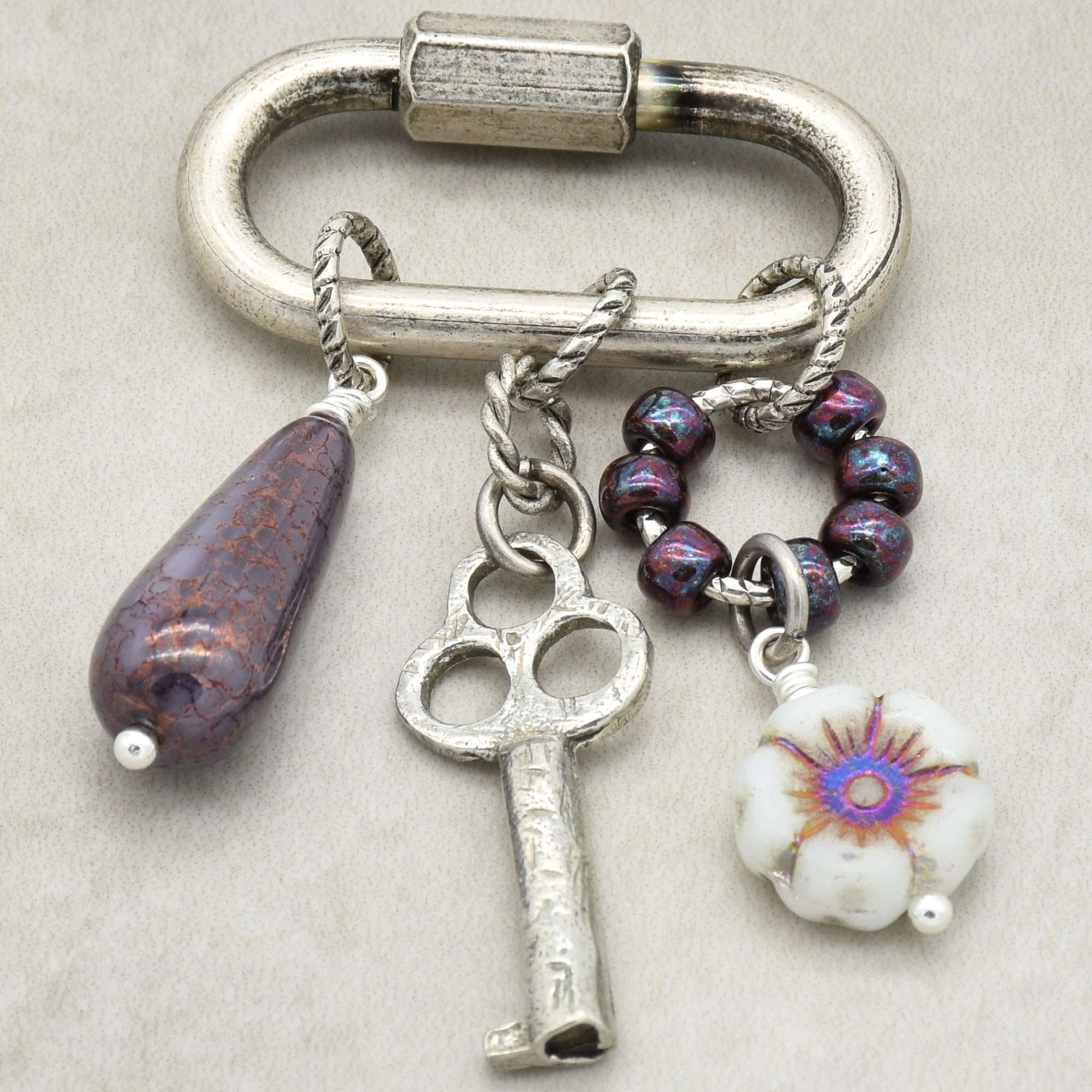 Keychain with various charms including a key, flower, and beads on a neutral background