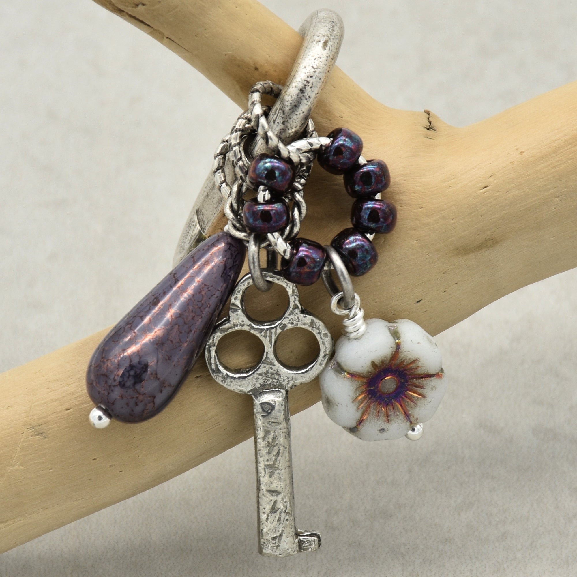 Keychain with key charm and purple beads on a wooden branch