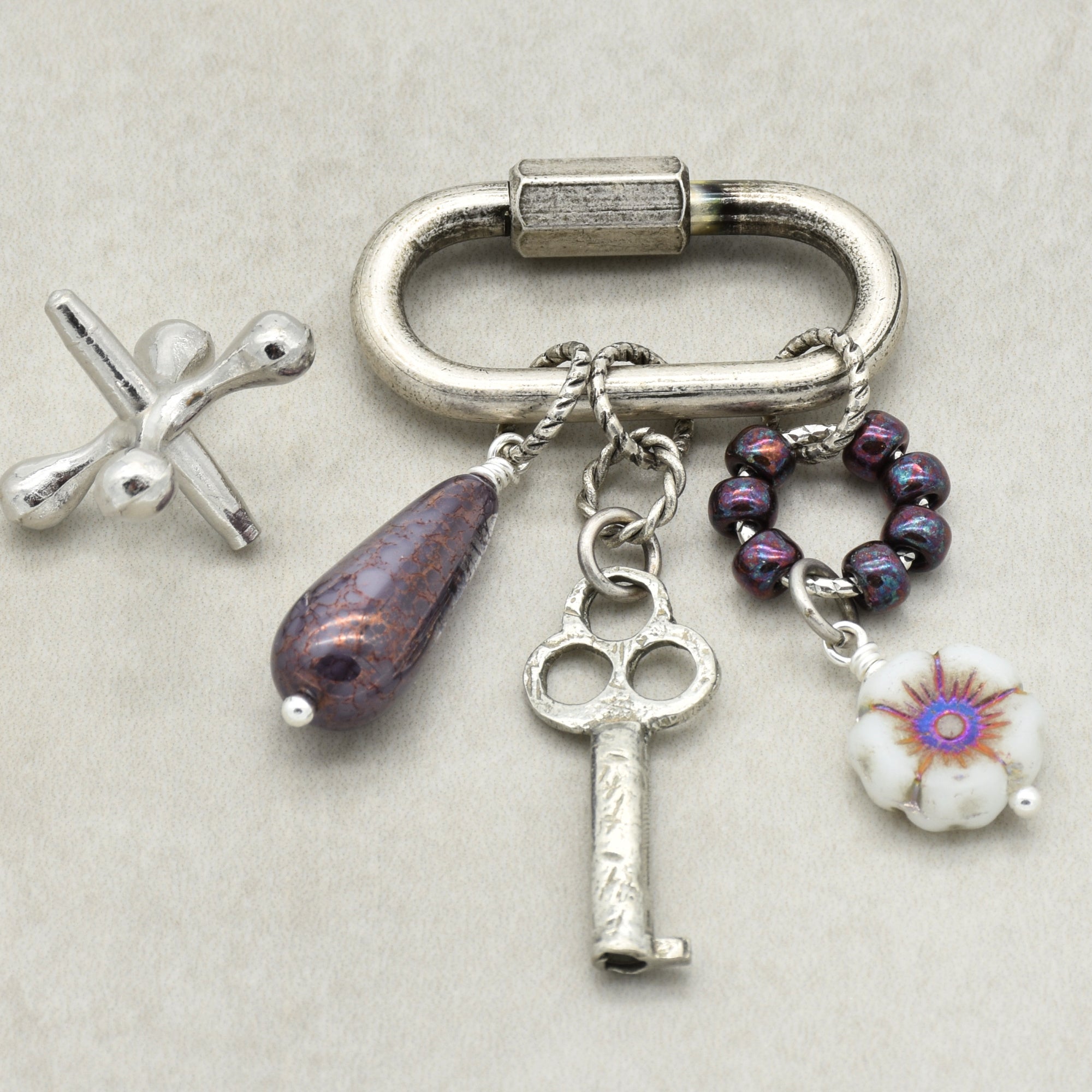 Keychain with various charms including a key and flower, on a light background