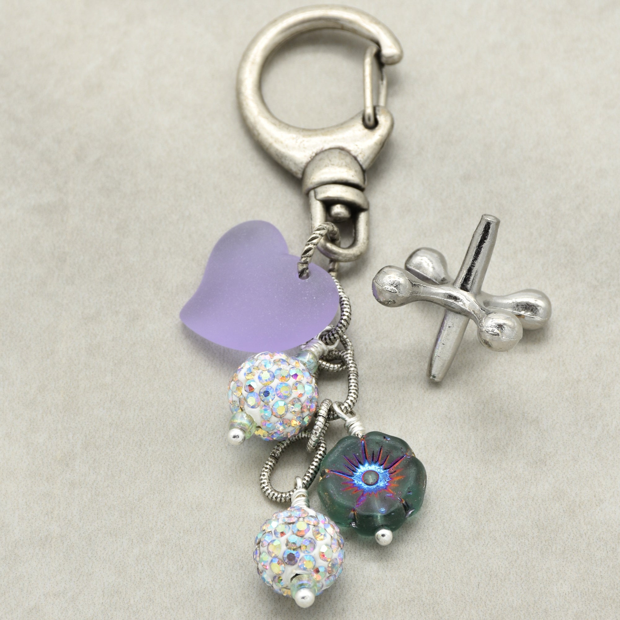 Keychain with heart, flower, and pave bead charms on a beige background