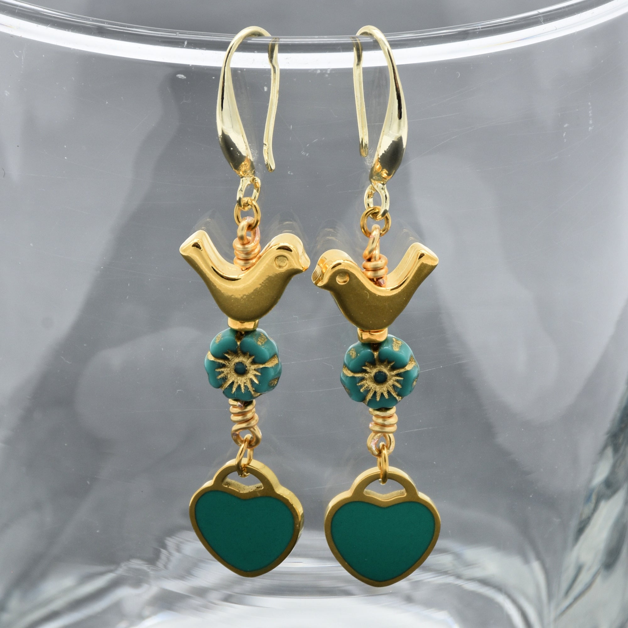 Lovebirds Turquoise Blue dangle earrings with gold birds and heart charms on a glass surface - handmade with love by Ruby Acorn