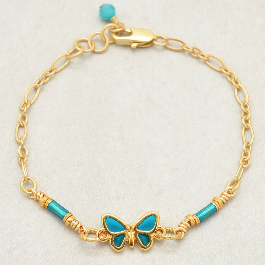 Gold bracelet with turquoise beads and butterfly charm on a light gray background - tell your story with art you can wear by Ruby Acorn