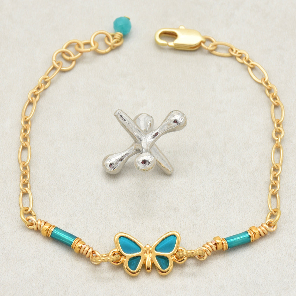 Gold bracelet with turquoise beads and a butterfly charm on a light gray background - wearable art by Ruby Acorn