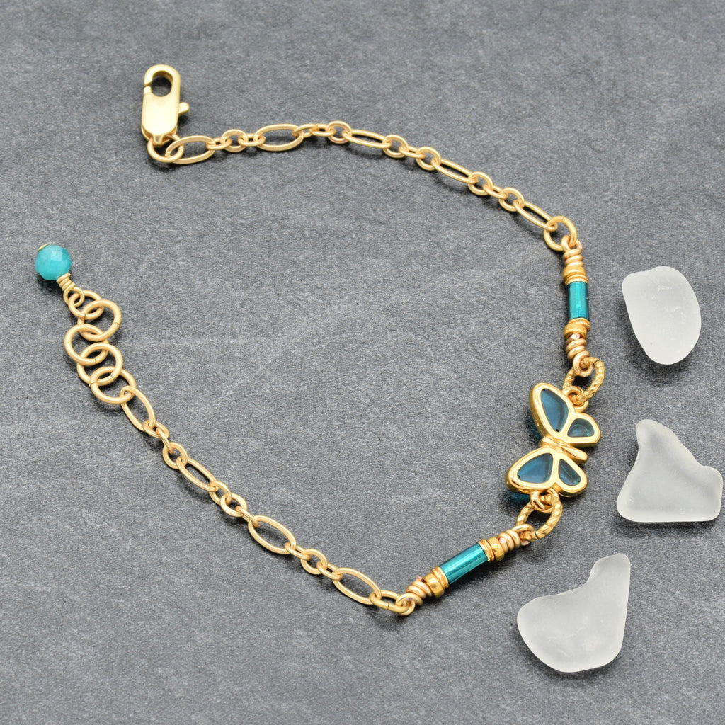 Gold bracelet with blue butterfly charm on a gray background - Made with love by Ruby Acorn