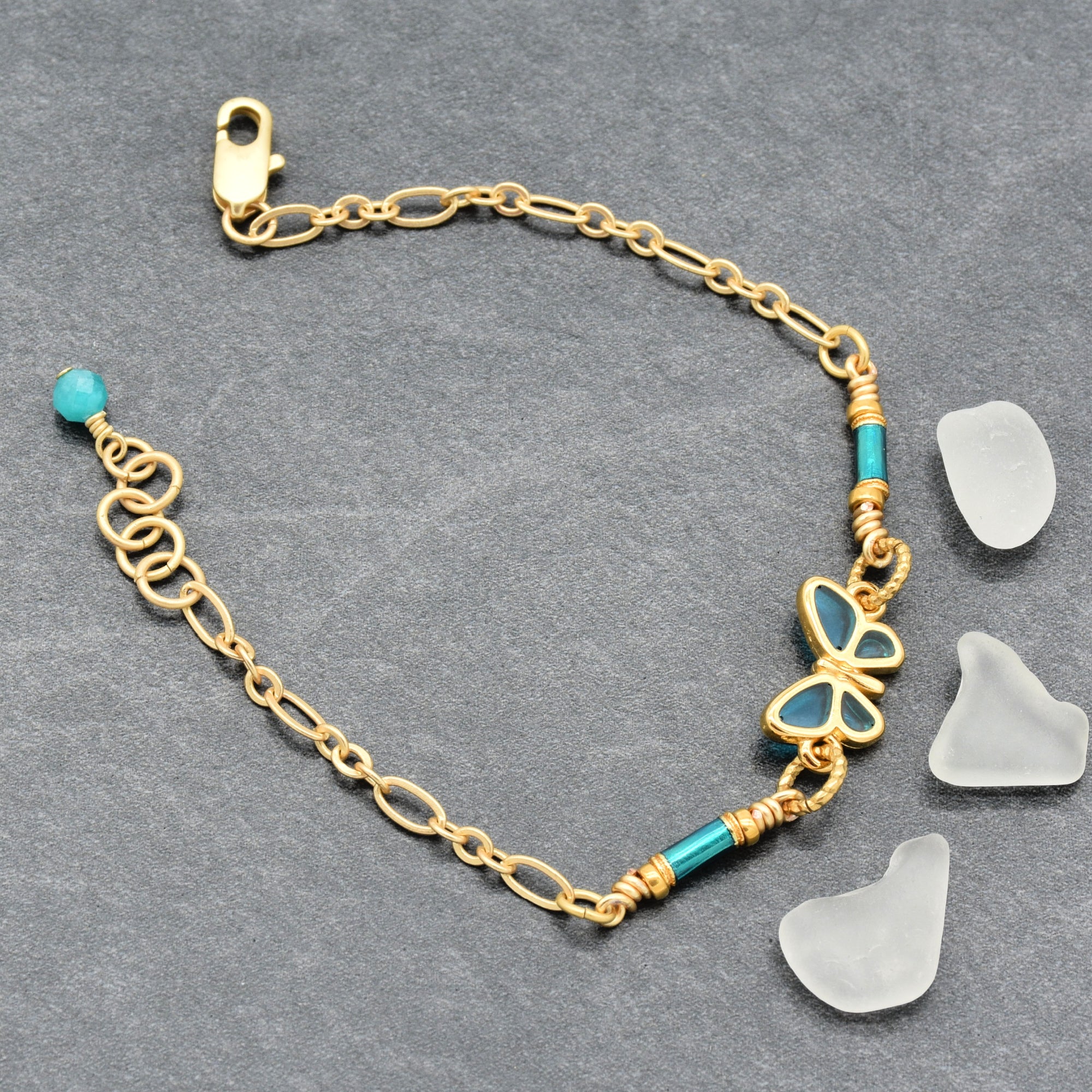 Gold bracelet with blue butterfly charm on a gray background - Made with love by Ruby Acorn