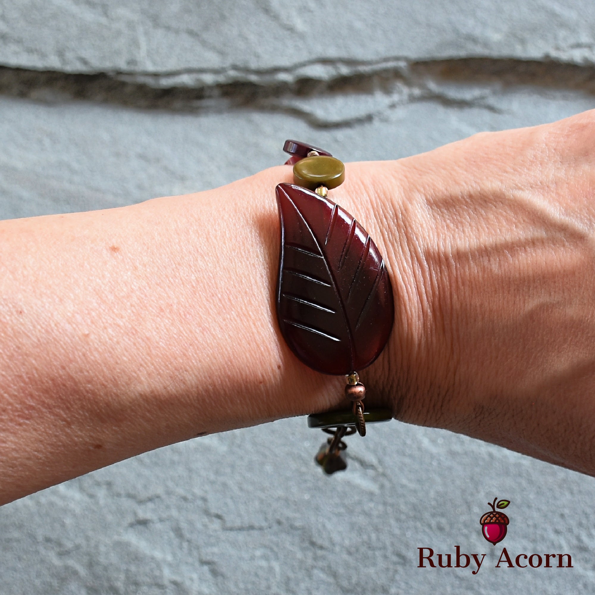This image shows a bracelet. It is worn around the wrist and features a leaf-shaped decorative element along with other beads.