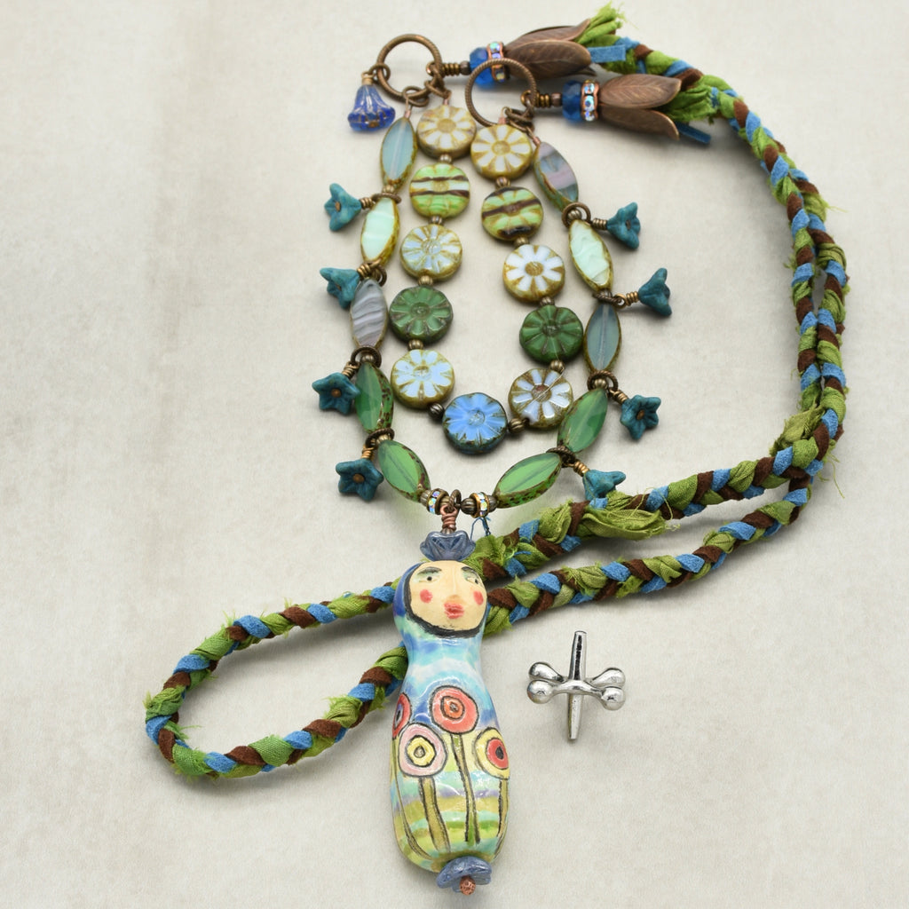 Colorful necklace with ceramic beads and a figurine pendant on a beige background