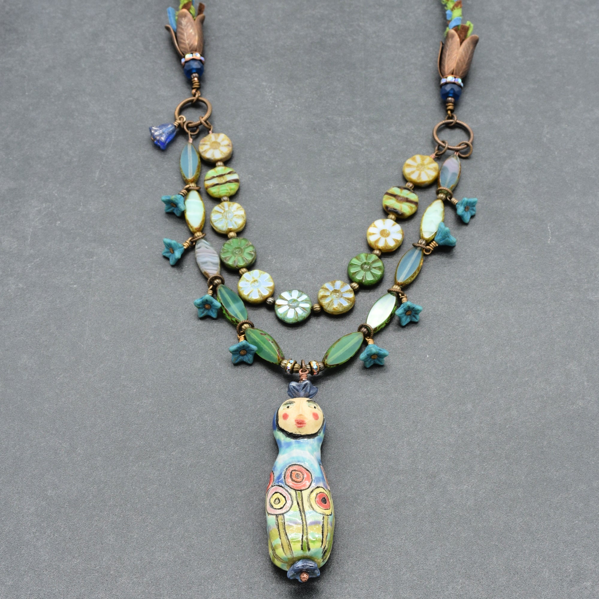 Colorful beaded necklace with a unique pendant on a gray background