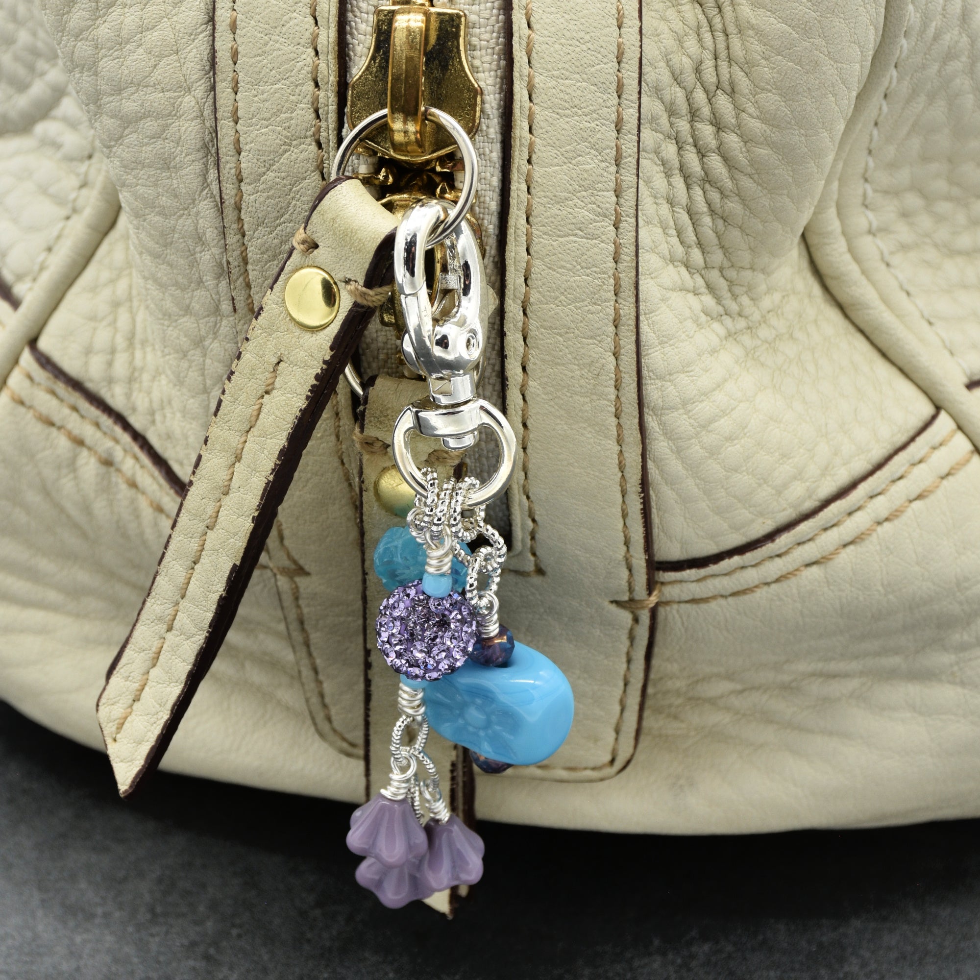 Beaded keychain attached to a beige leather bag