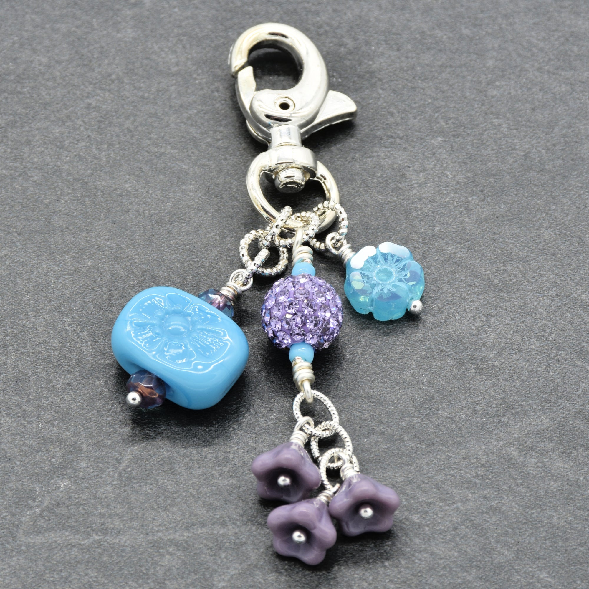 Decorative charm with blue and purple beads on a gray background