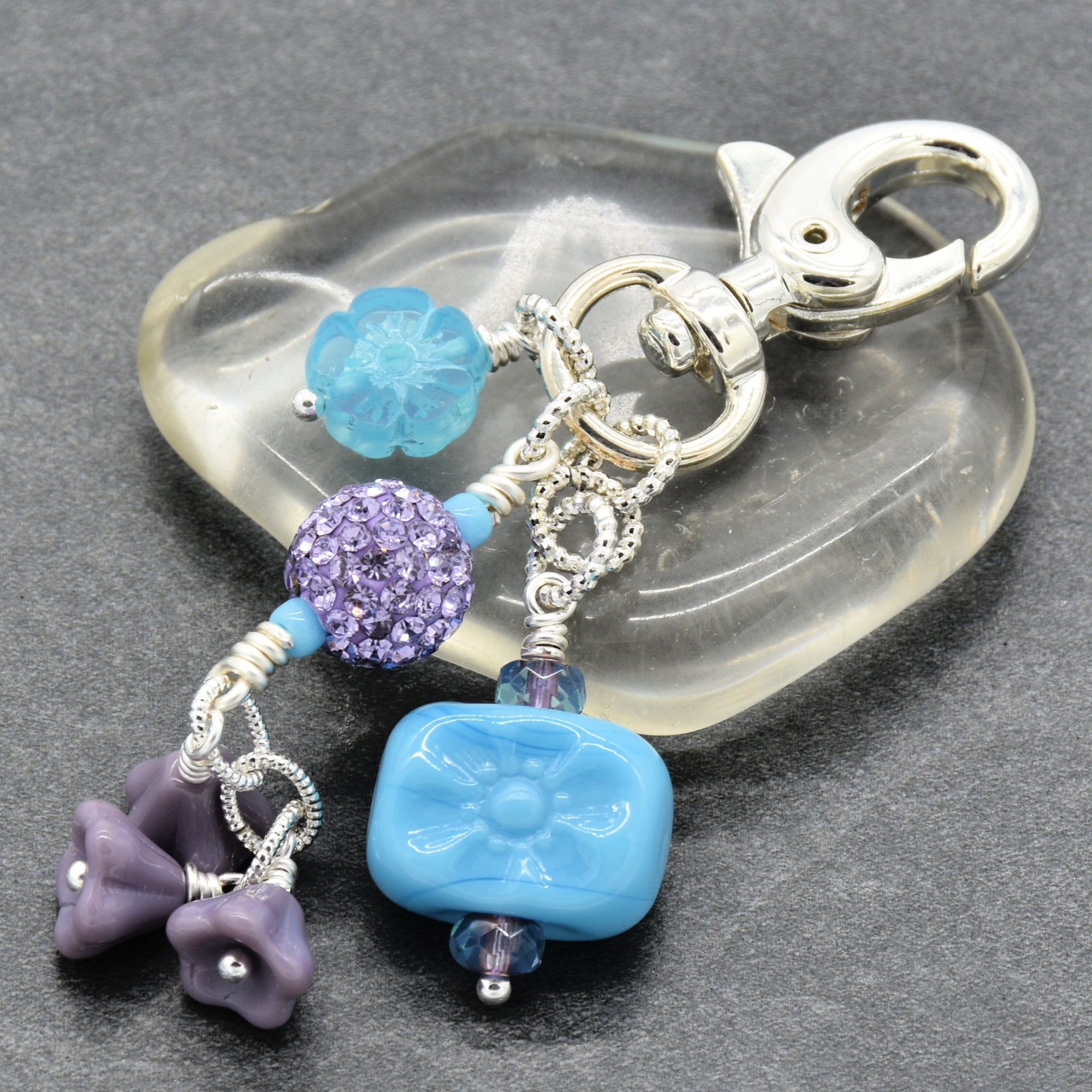Decorative keychain with blue and purple beads on a gray background