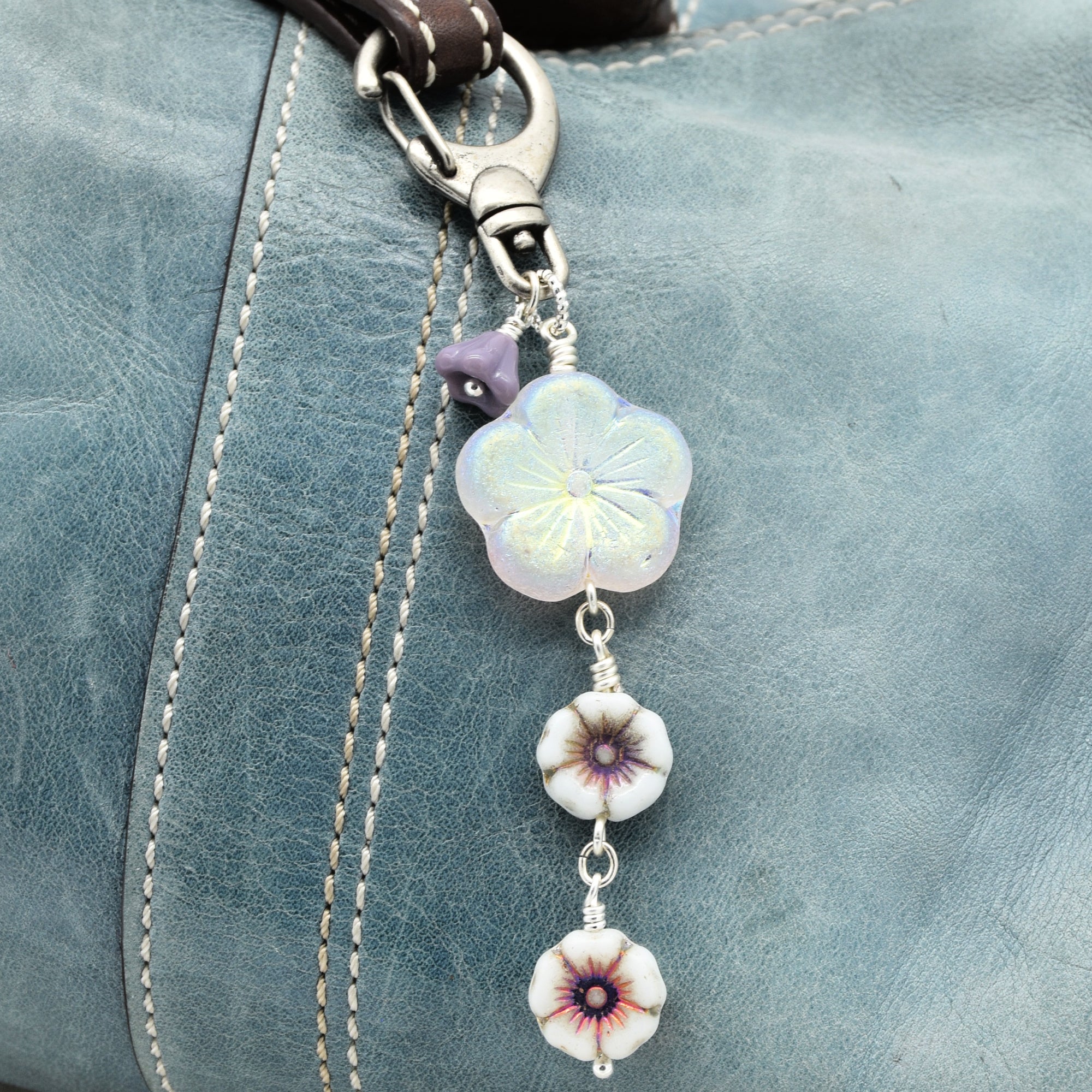 Decorative keychain with floral beads on a blue leather surface