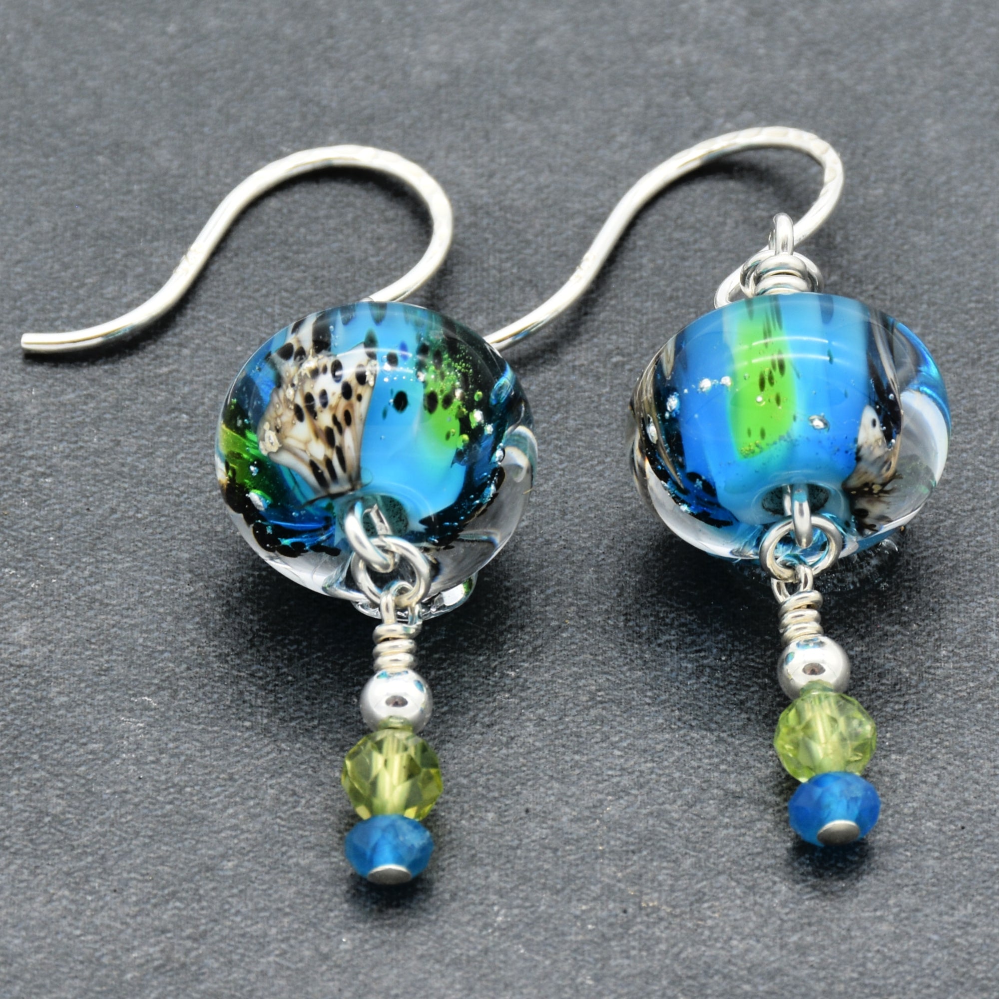 Colorful artisan lampwork glass earrings with sterling silver ear wires, peridot and apatite on a gray surface - handmade with love by Ruby Acorn